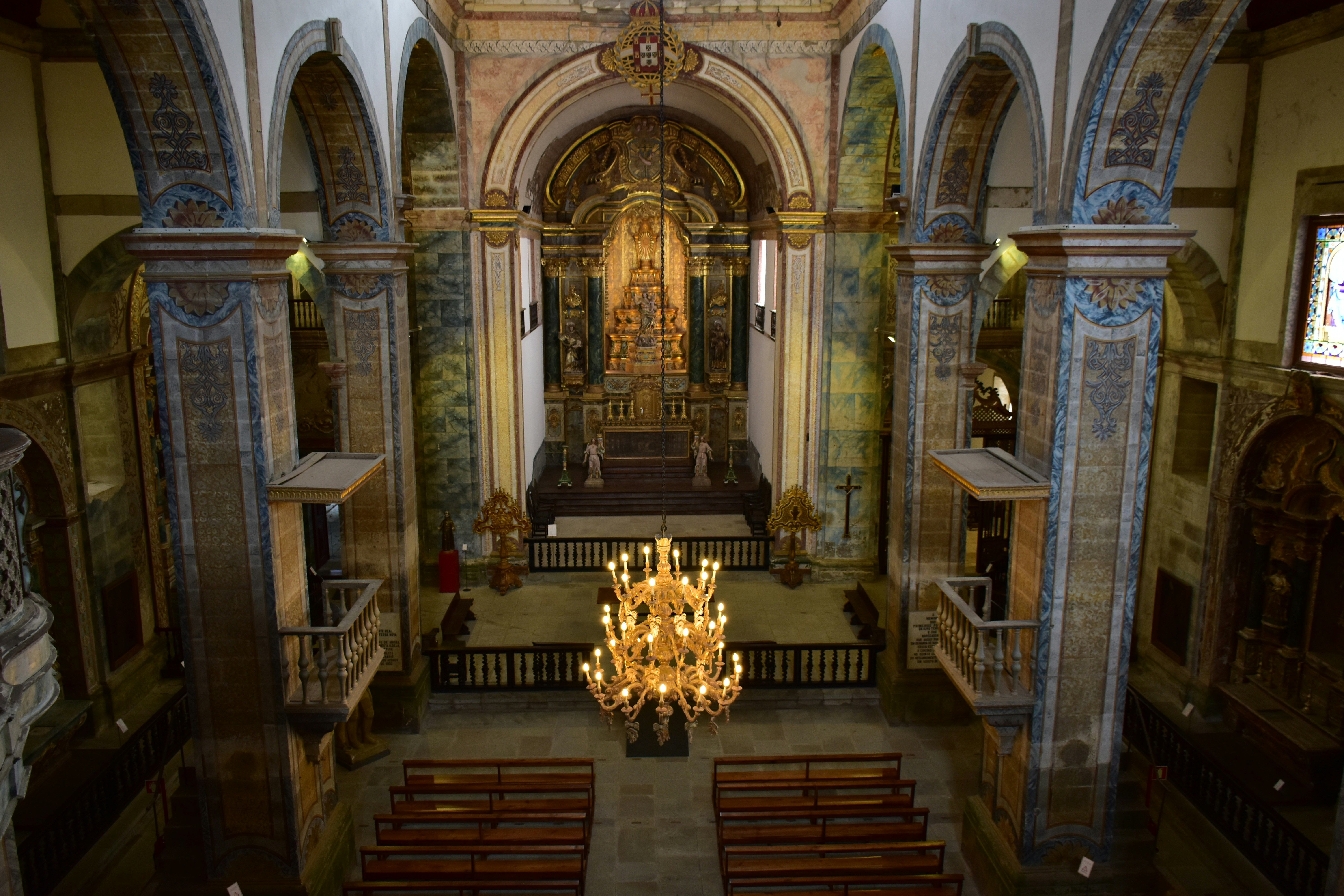 Ornate church interior with a grand chandelier and gilded altar.