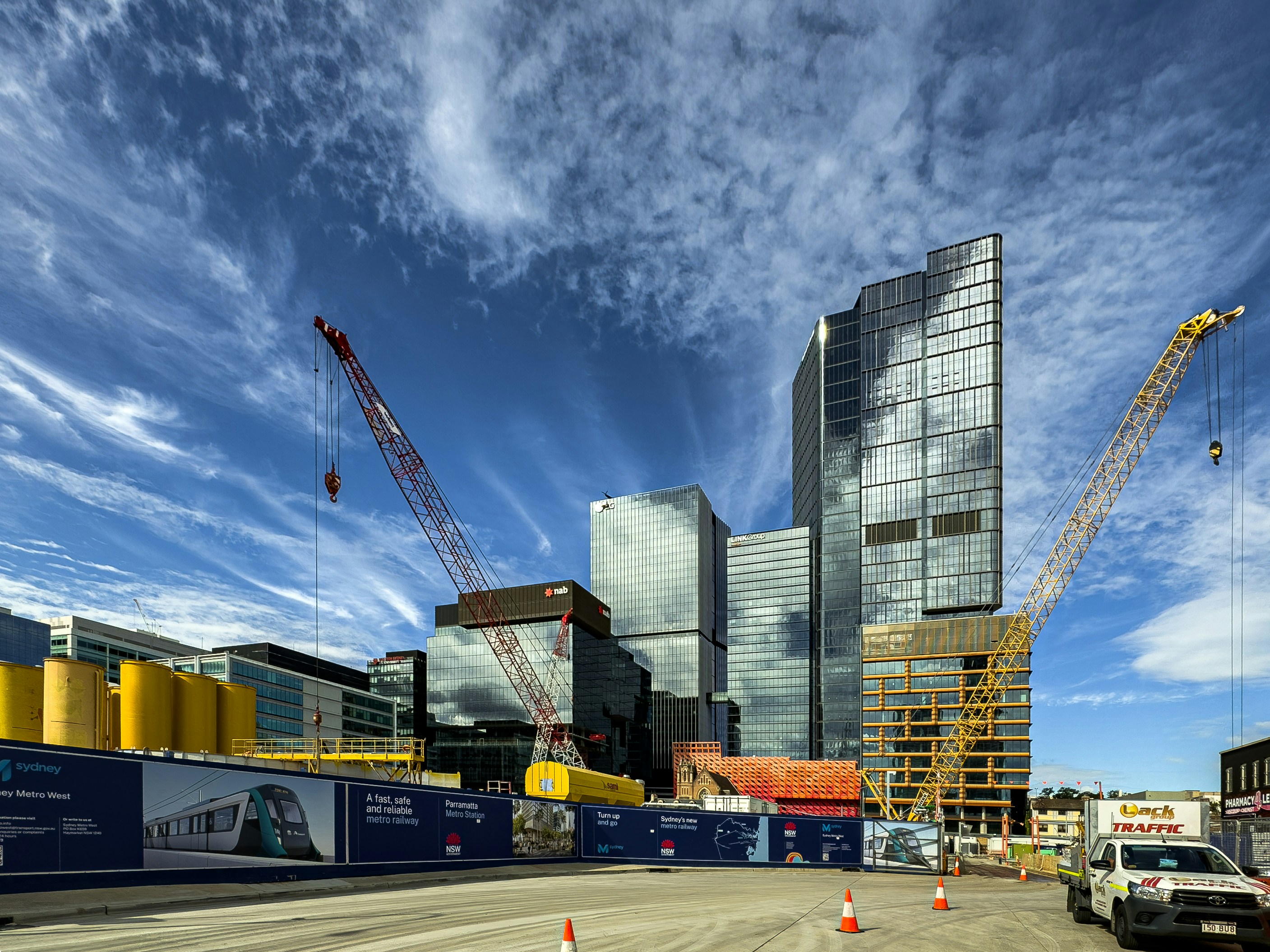 Modern skyscrapers under construction with cranes and blue sky.