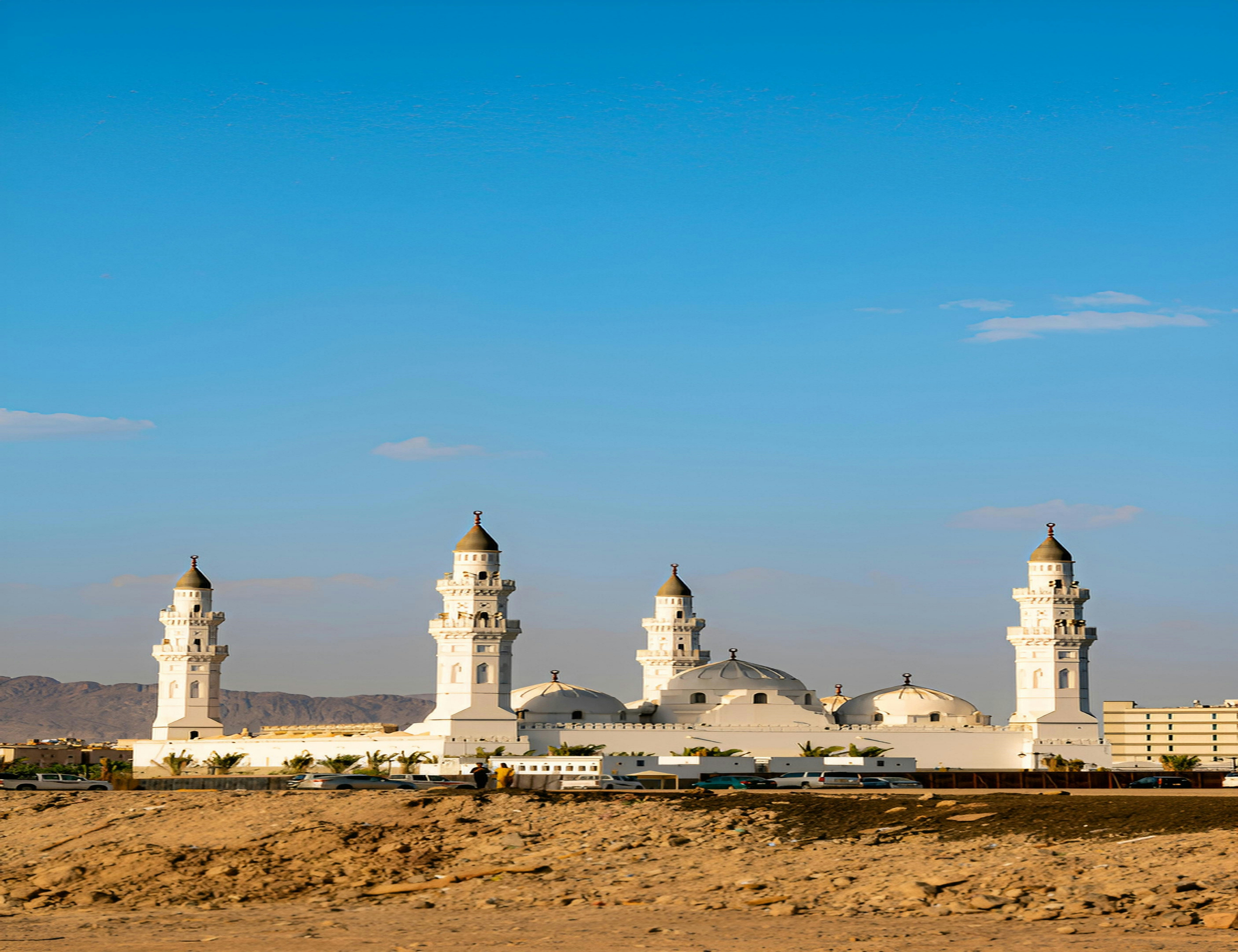 Masjid putih dengan beberapa menara di langit biru yang cerah.