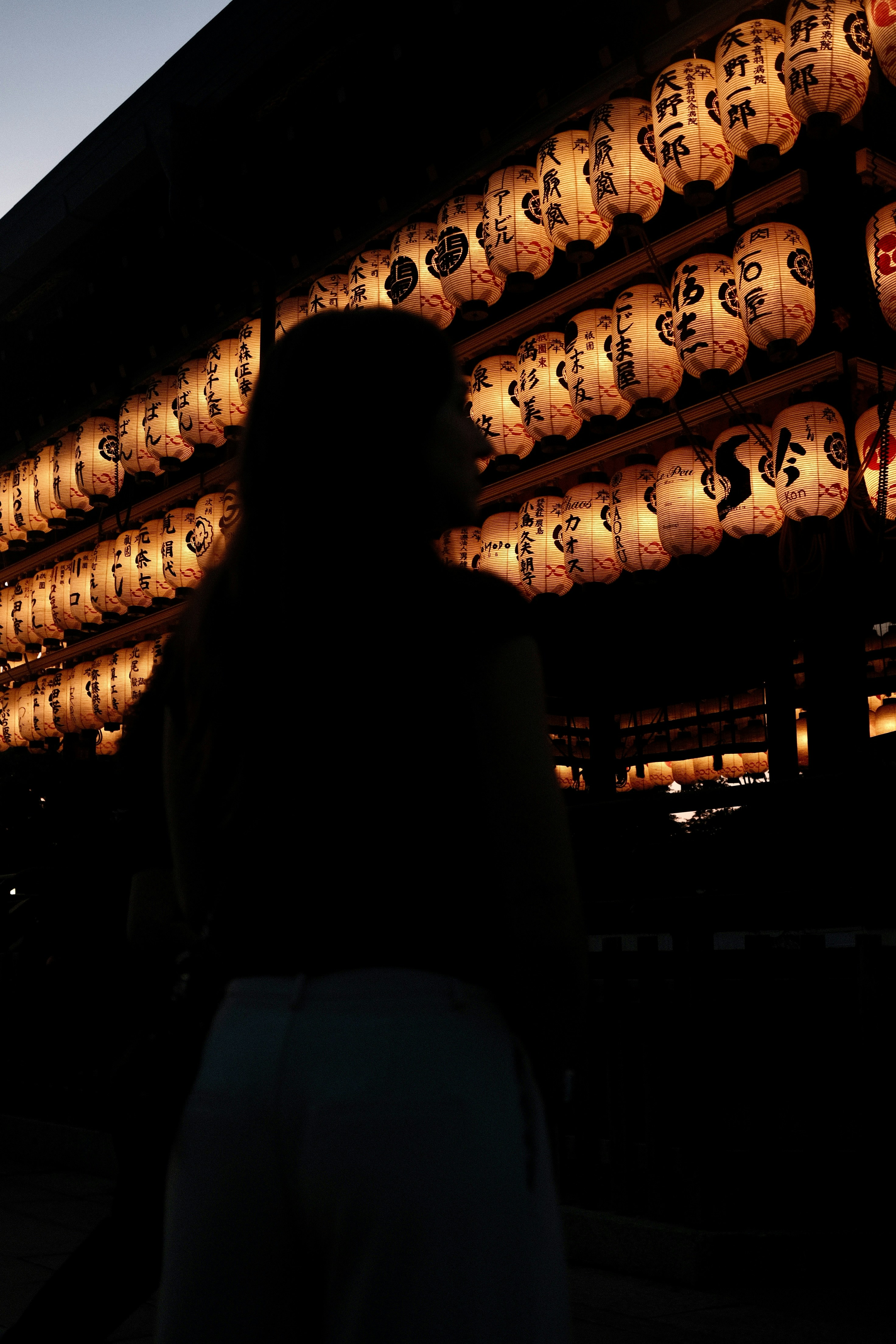 Silhouette of a person in front of glowing japanese lanterns