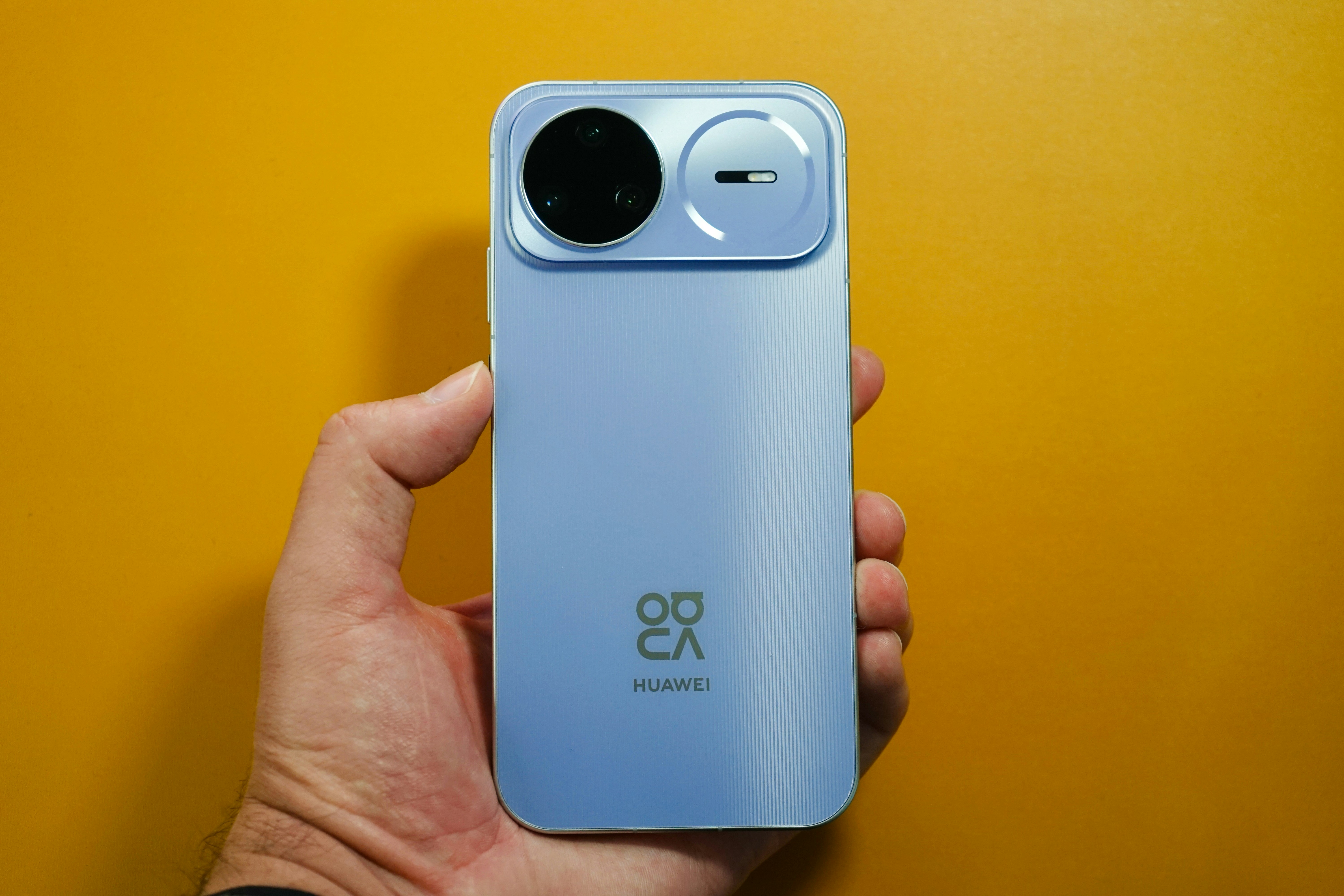 Smartphone bleu clair maintenu sur fond jaune