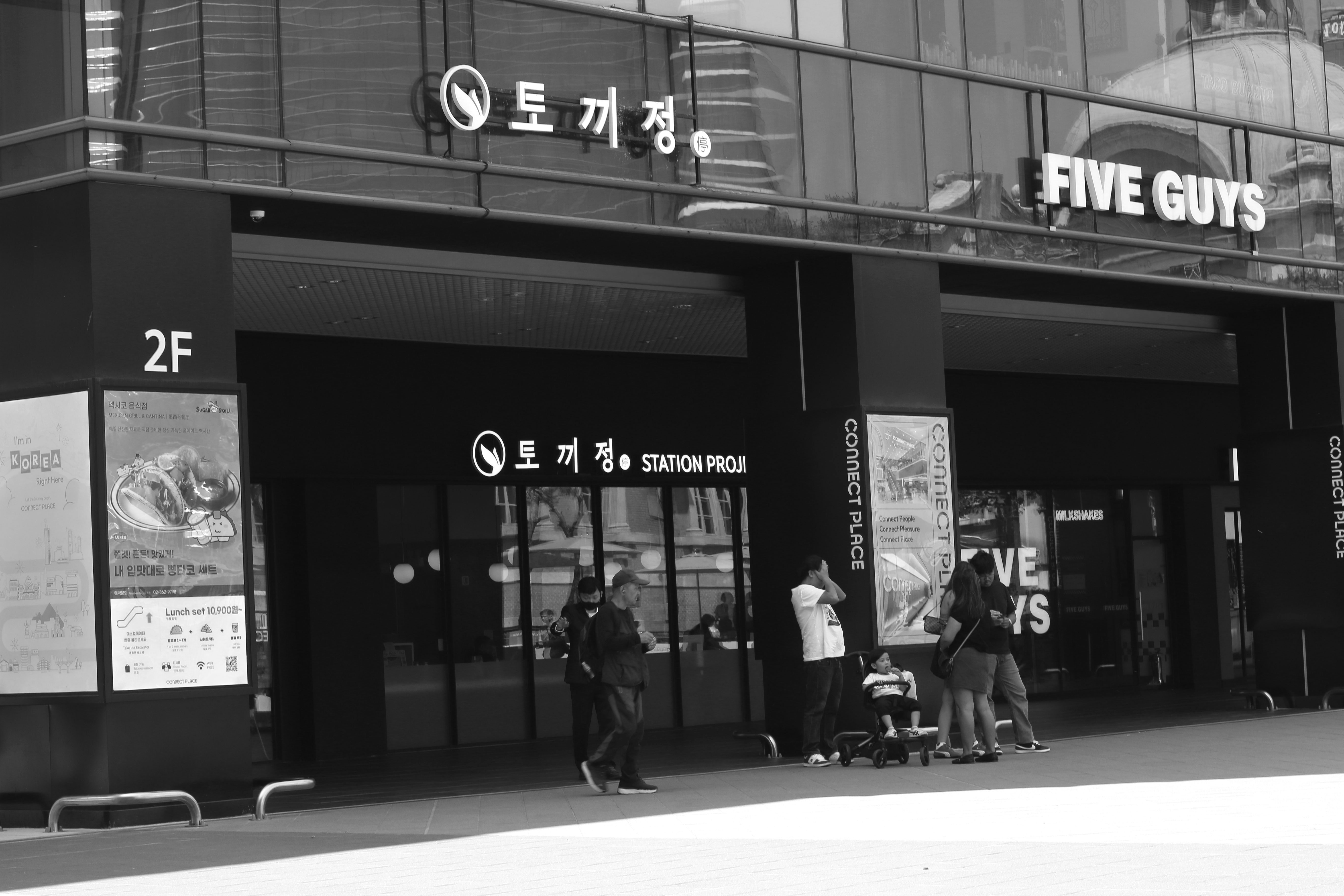 People outside a building with "five guys" sign.