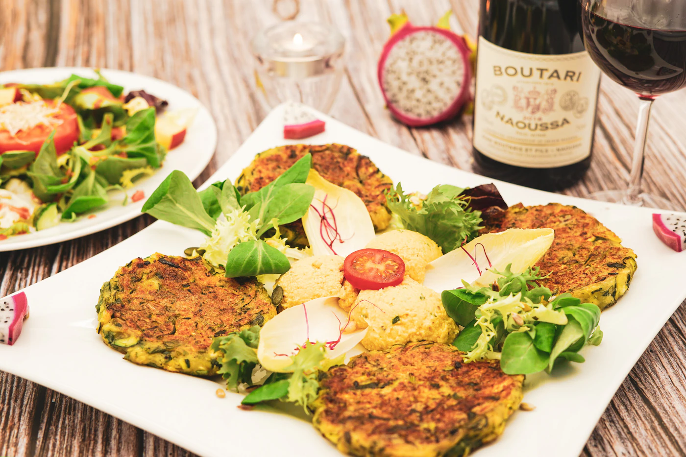 Golden zucchini fritters plated with leafy salad and a creamy dip