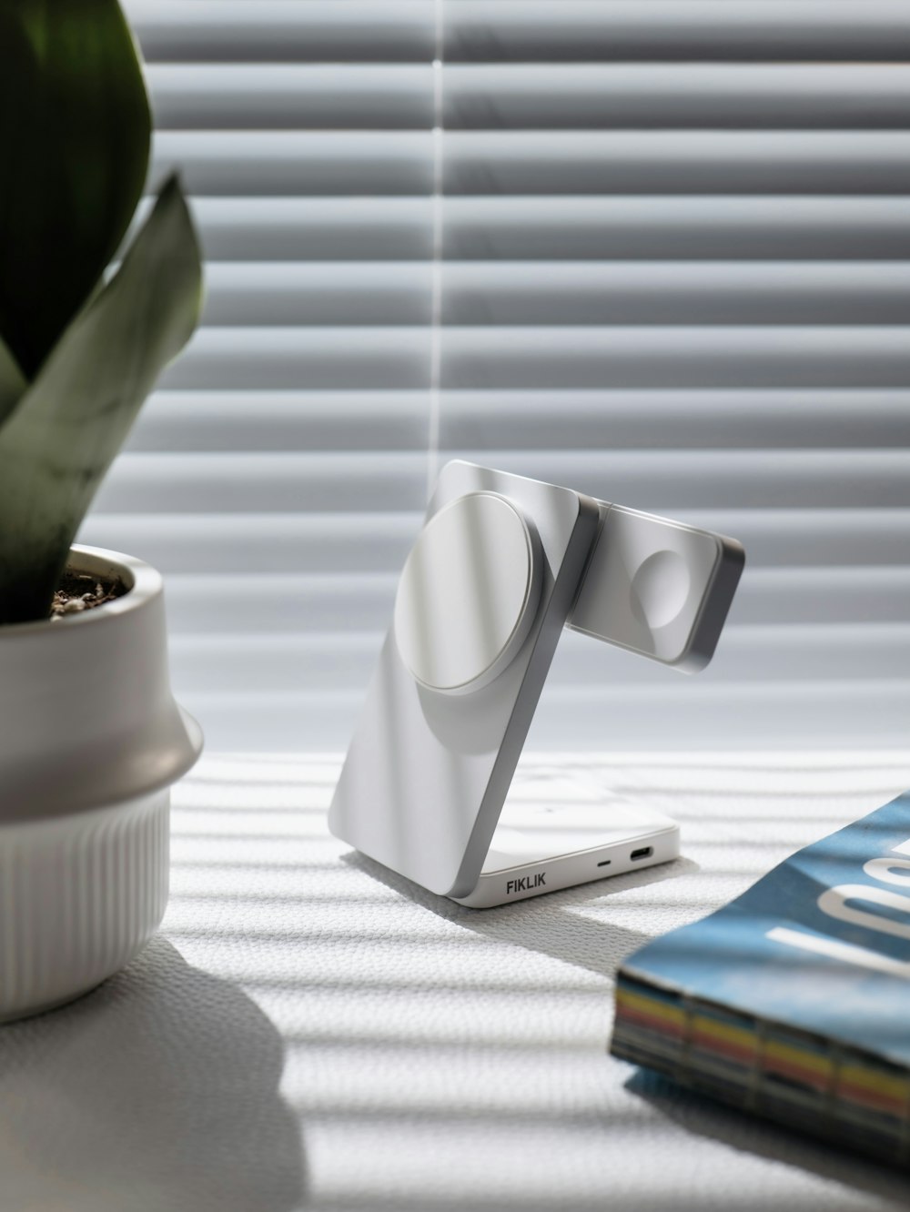 Compact silver charging stand with magnetic device pads and USB-C ports on a bright desk
