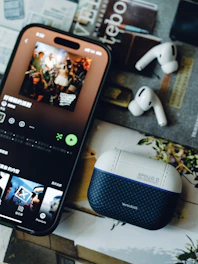 A smartphone playing music with wireless earbuds and a case.