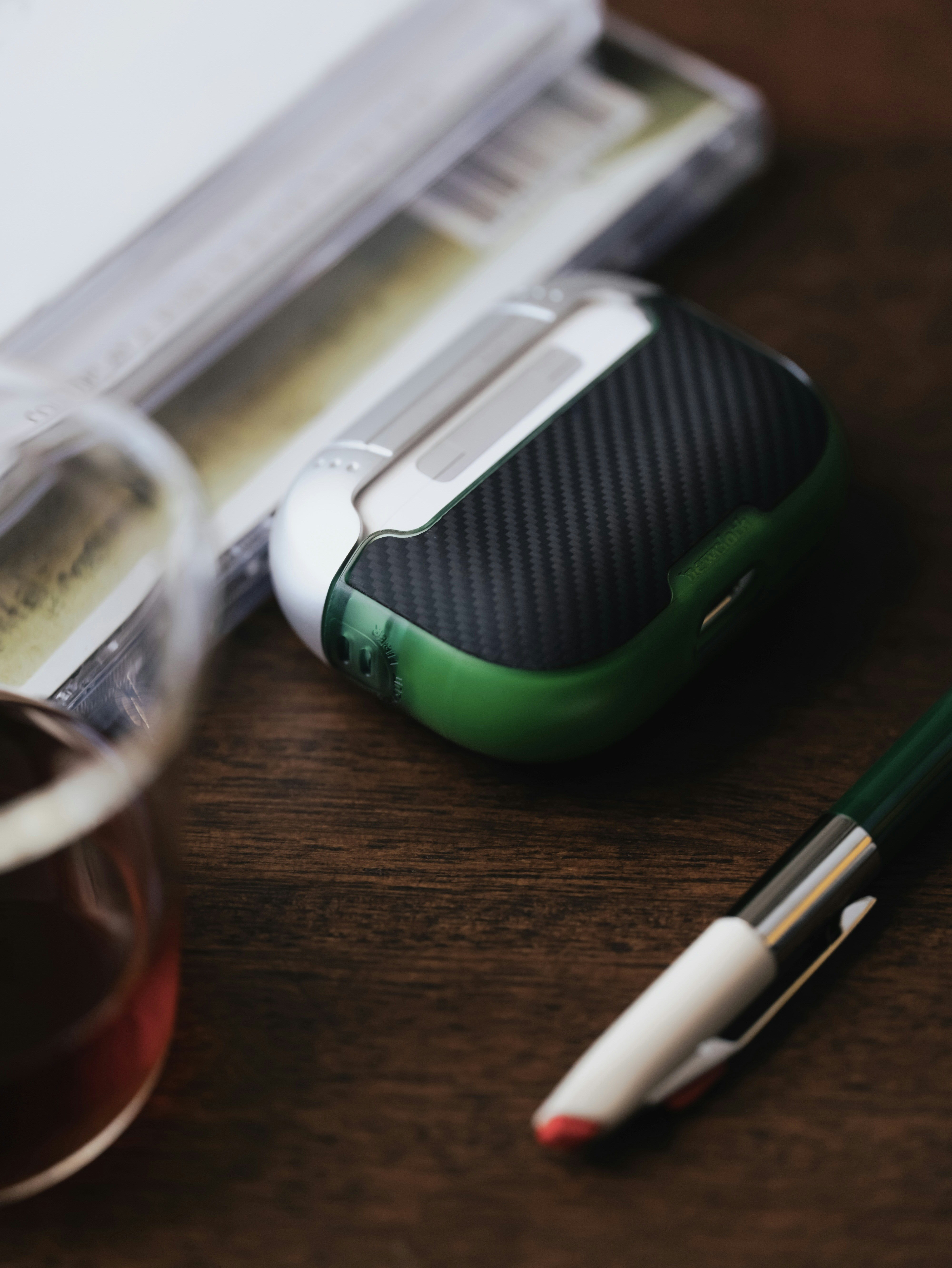 Funda para auriculares, bolígrafo y bebida sobre una mesa de madera