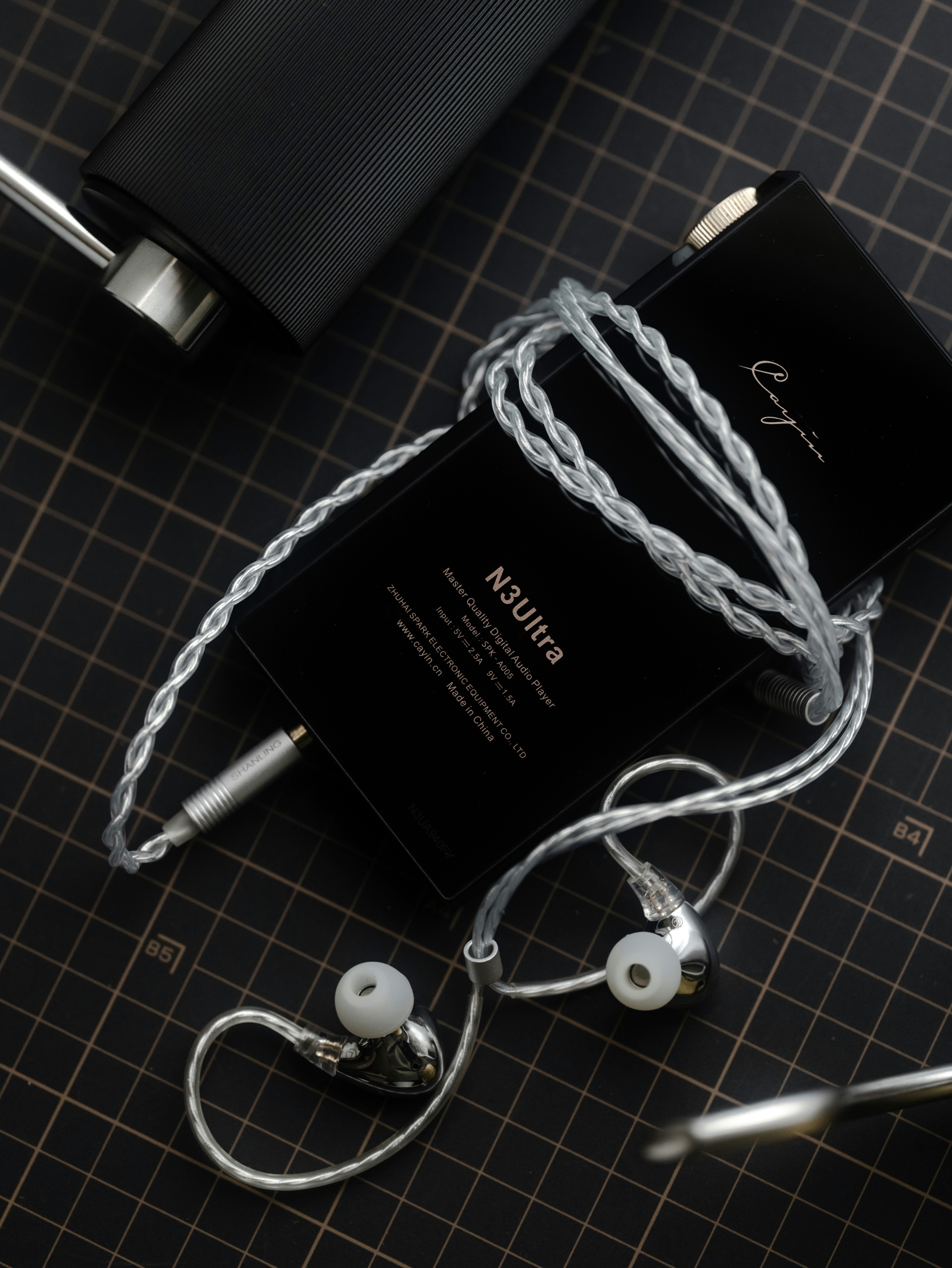 Silver in-ear monitors with a braided cable and black case.