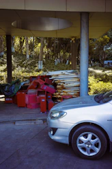 Silver car parked next to red bins and metal poles