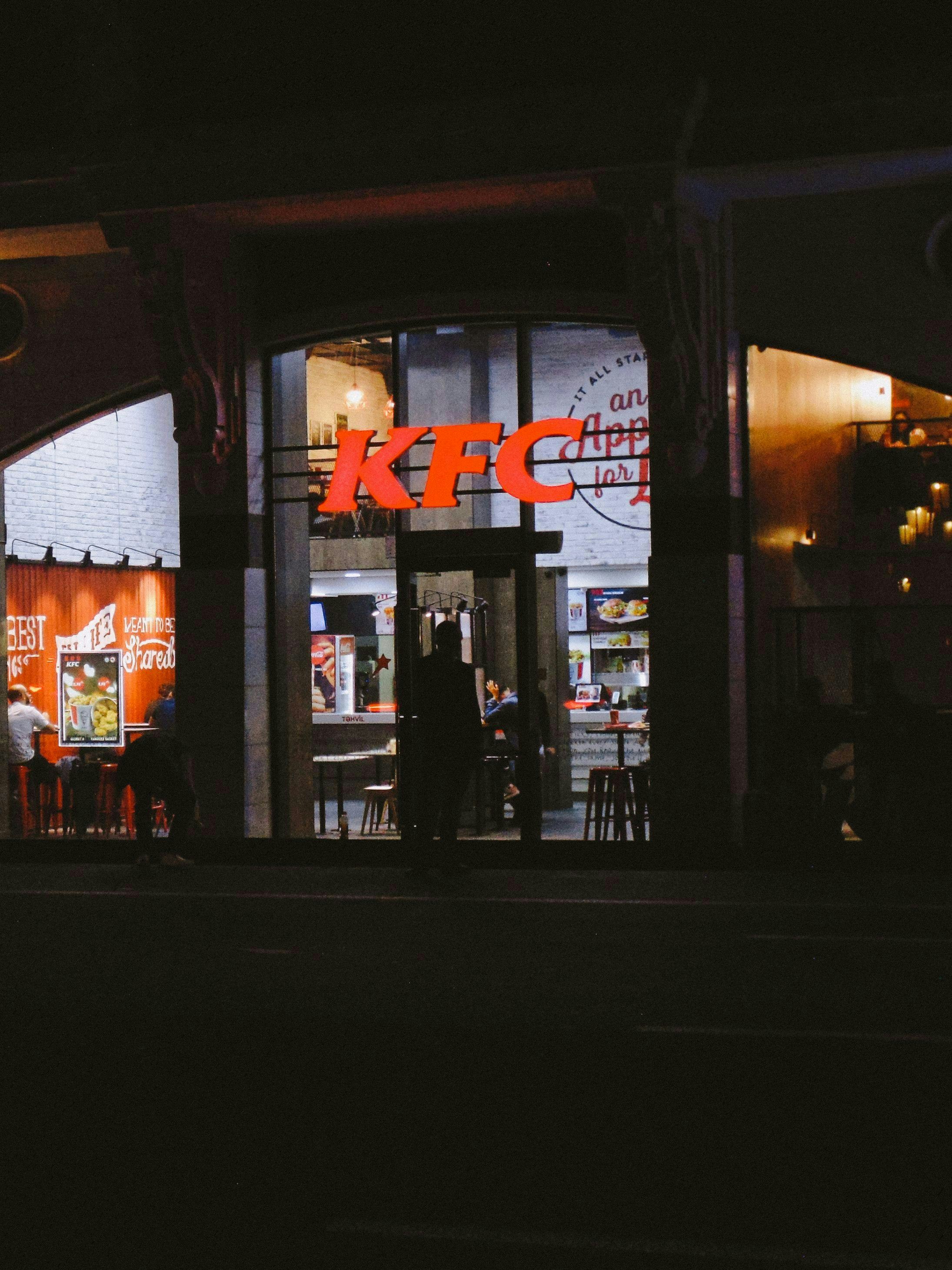 Restaurant KFC éclairé la nuit avec des gens à l’intérieur