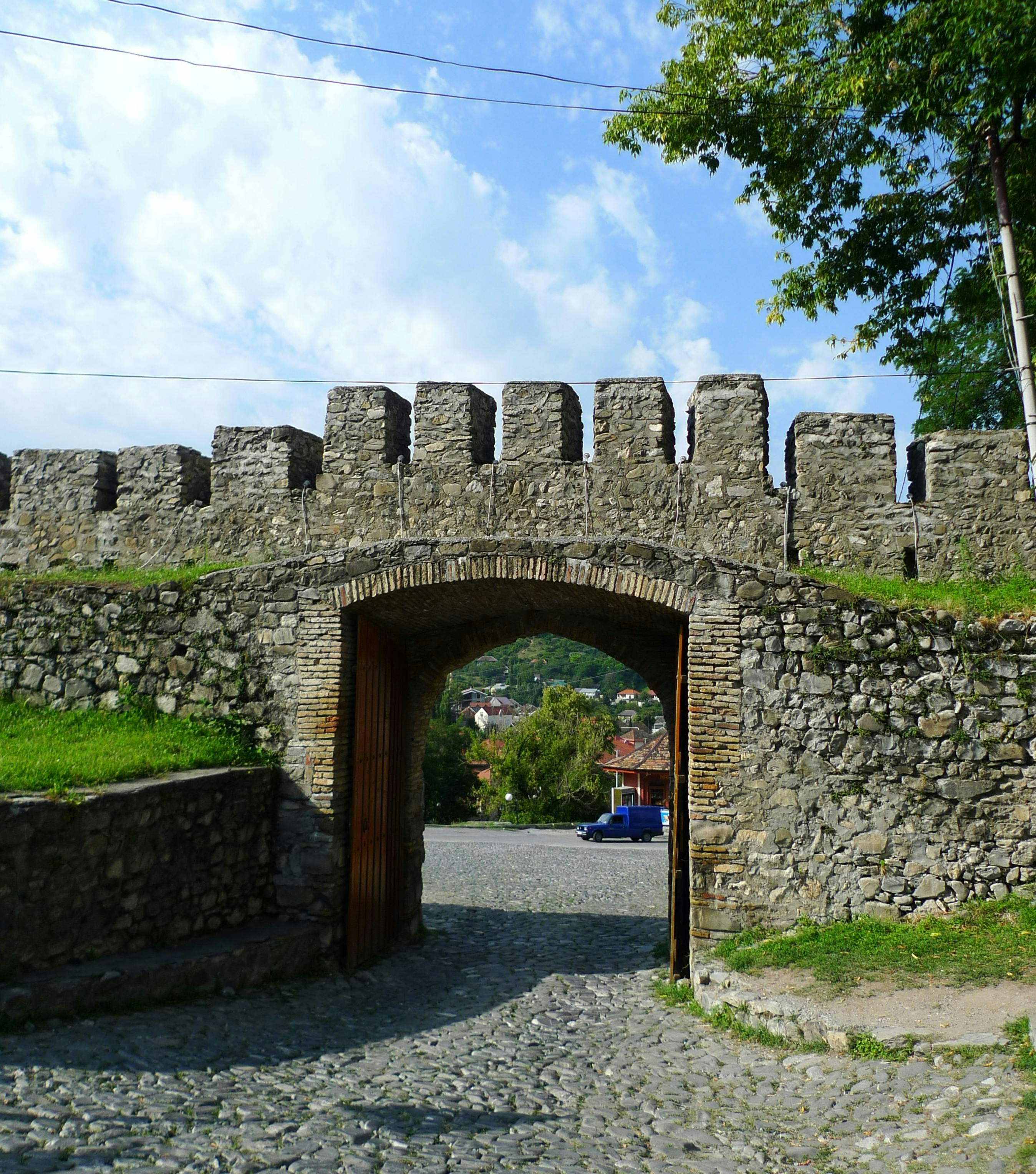 Gerbang benteng batu dengan benteng berkrenellasi dan gapura.