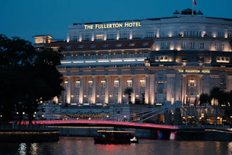 The fullerton hotel illuminated at night with a red bridge