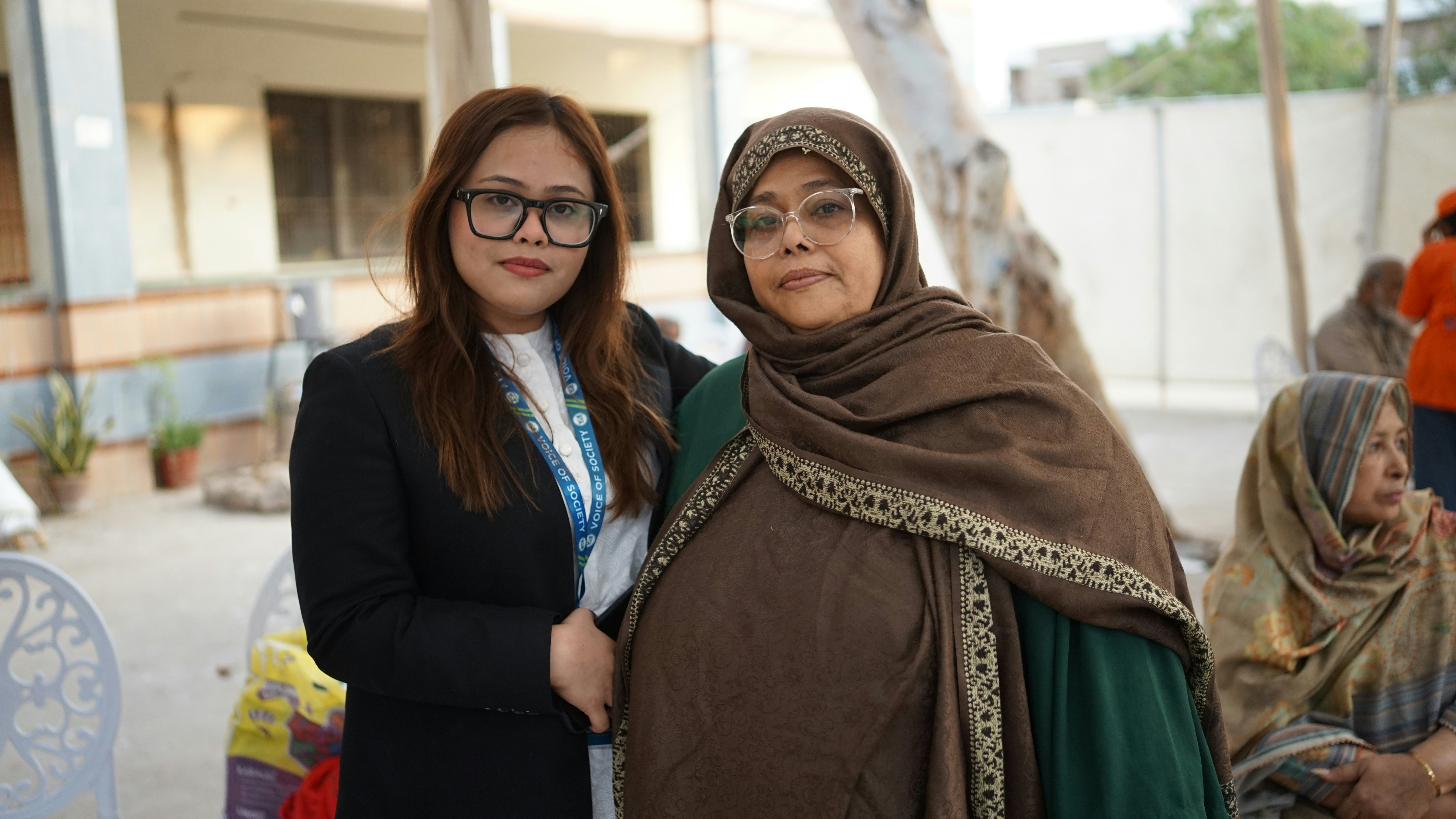 Dua wanita berdiri berdekatan di luar ruangan
