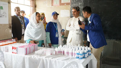 Health workers and officials with medicine bottles on a table.