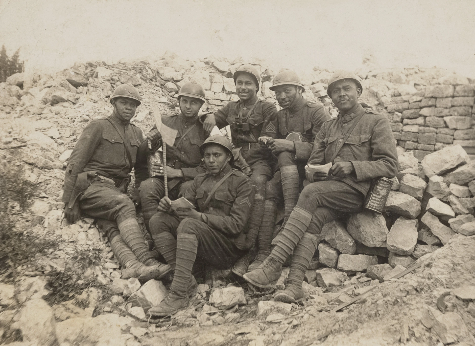 Six soldiers pose together in front of rubble