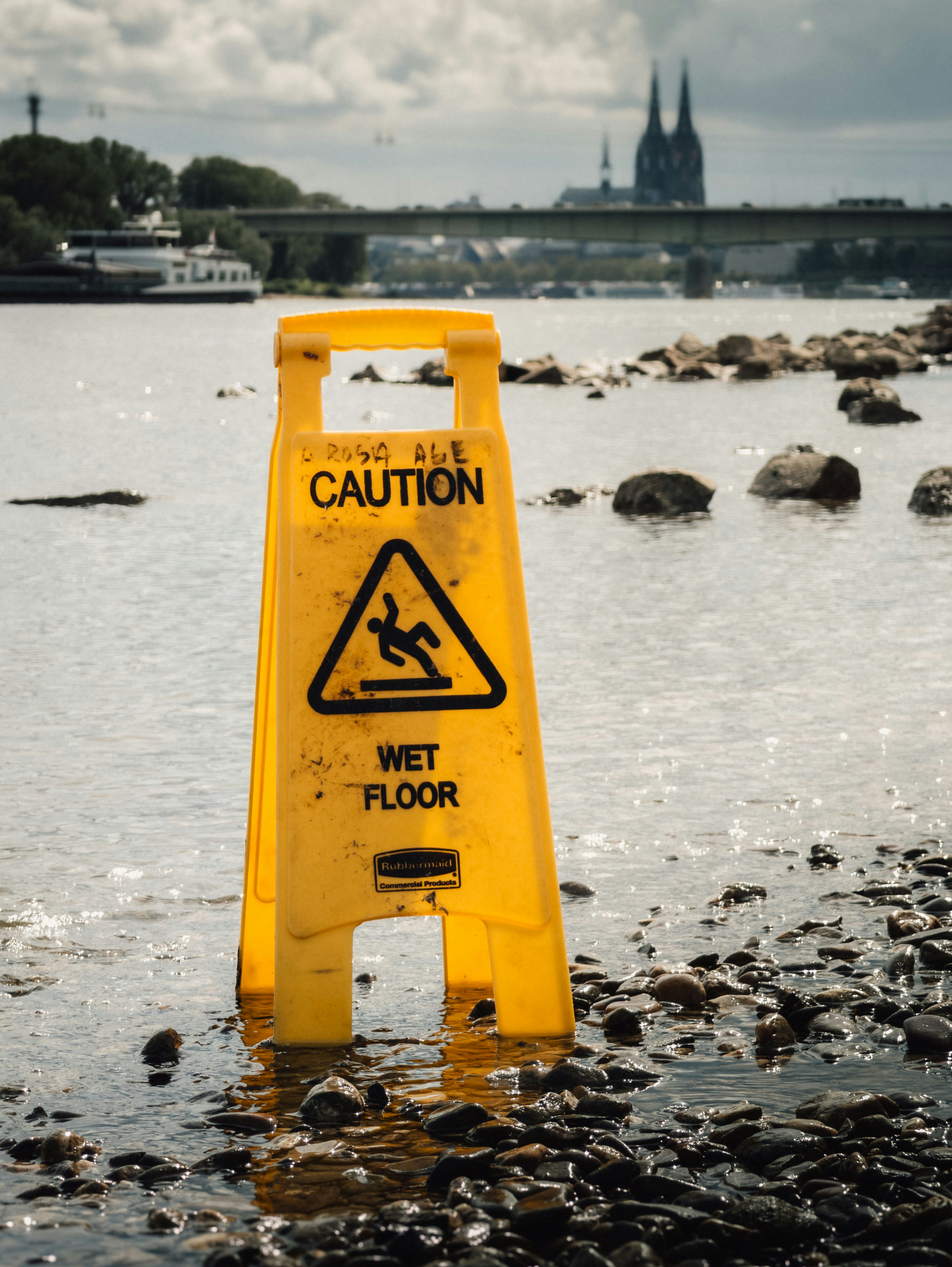 Yellow caution sign in water near shore
