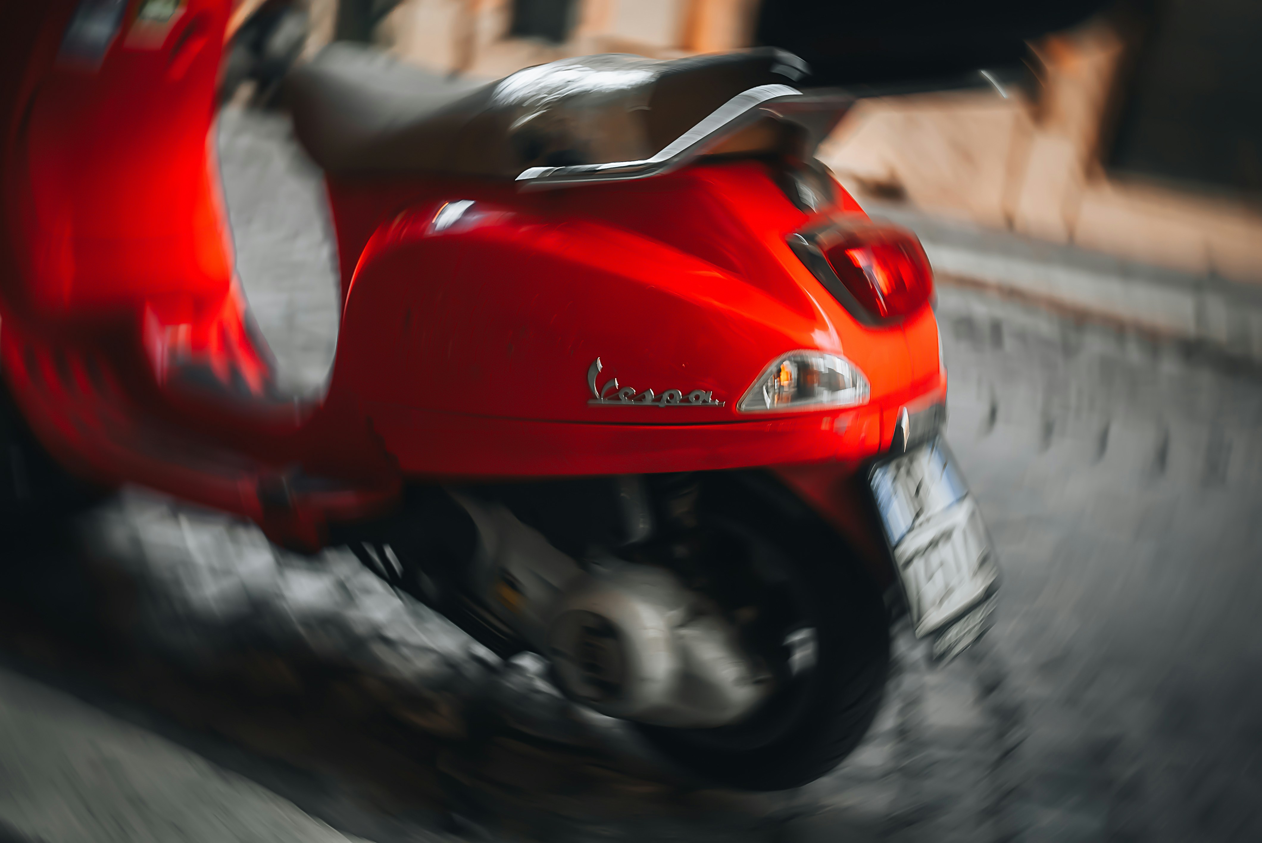 A red vespa scooter with motion blur on a street.