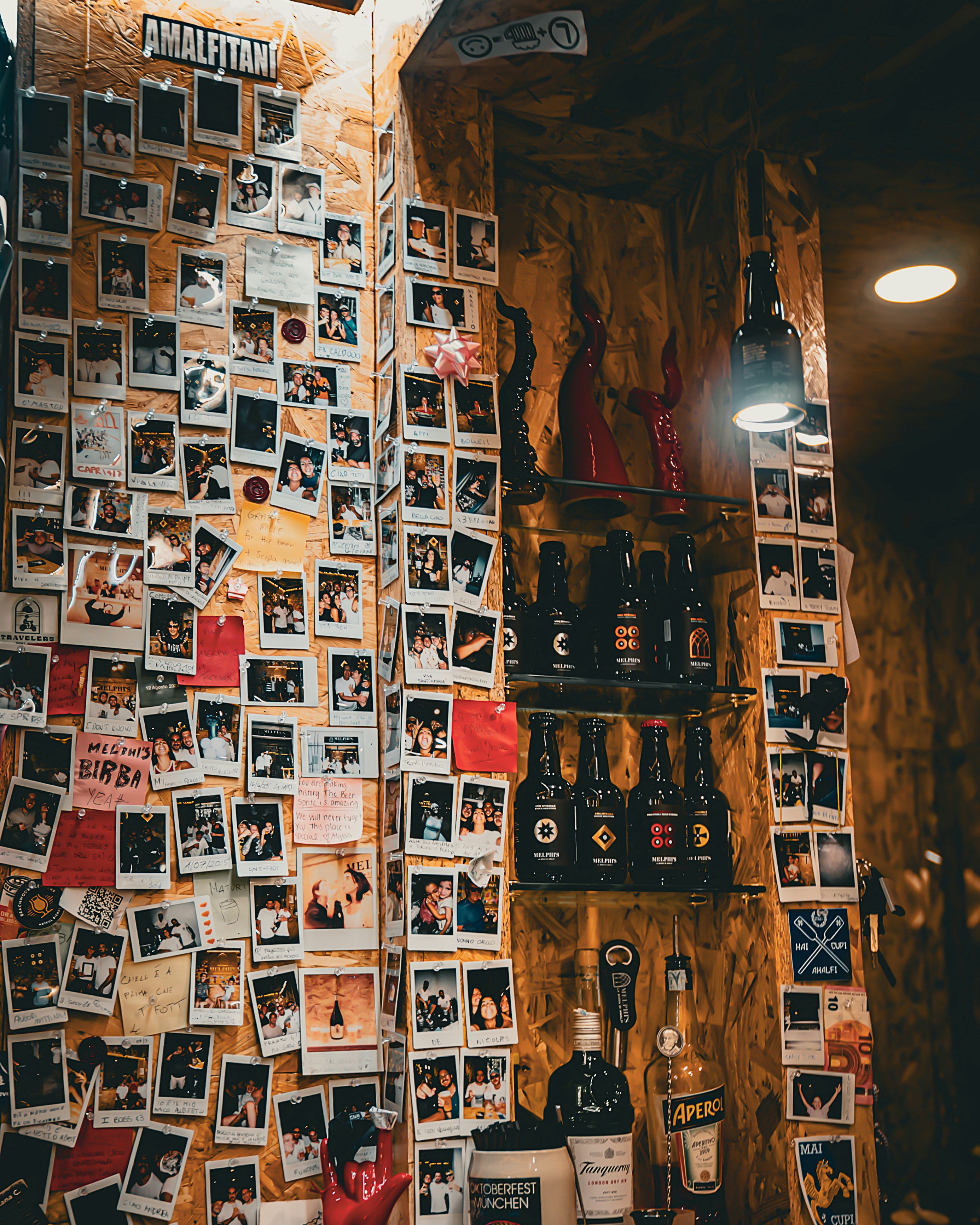 Wall covered in polaroid photos and bottles of alcohol.