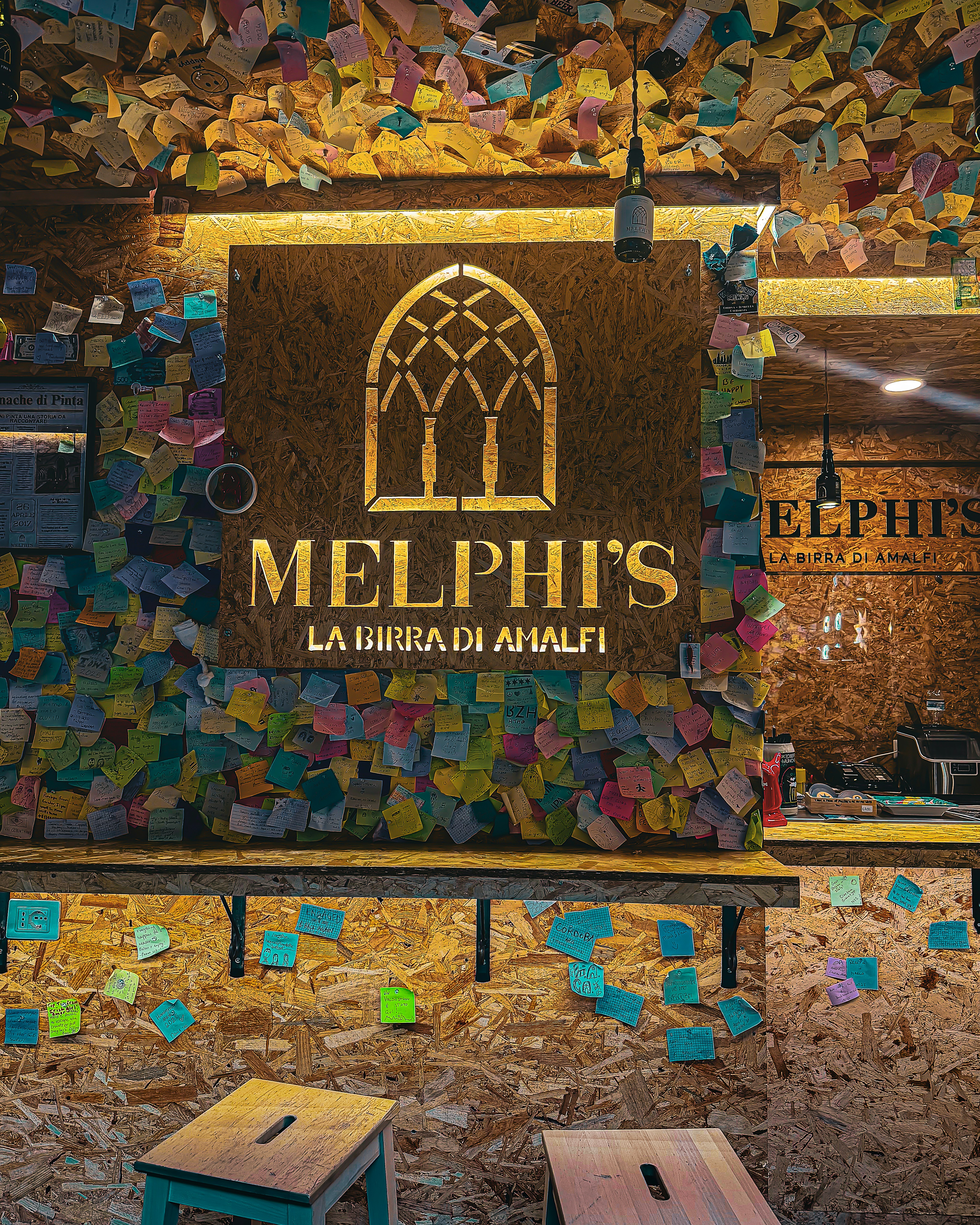 Melphi's beer sign on a wall covered with sticky notes.