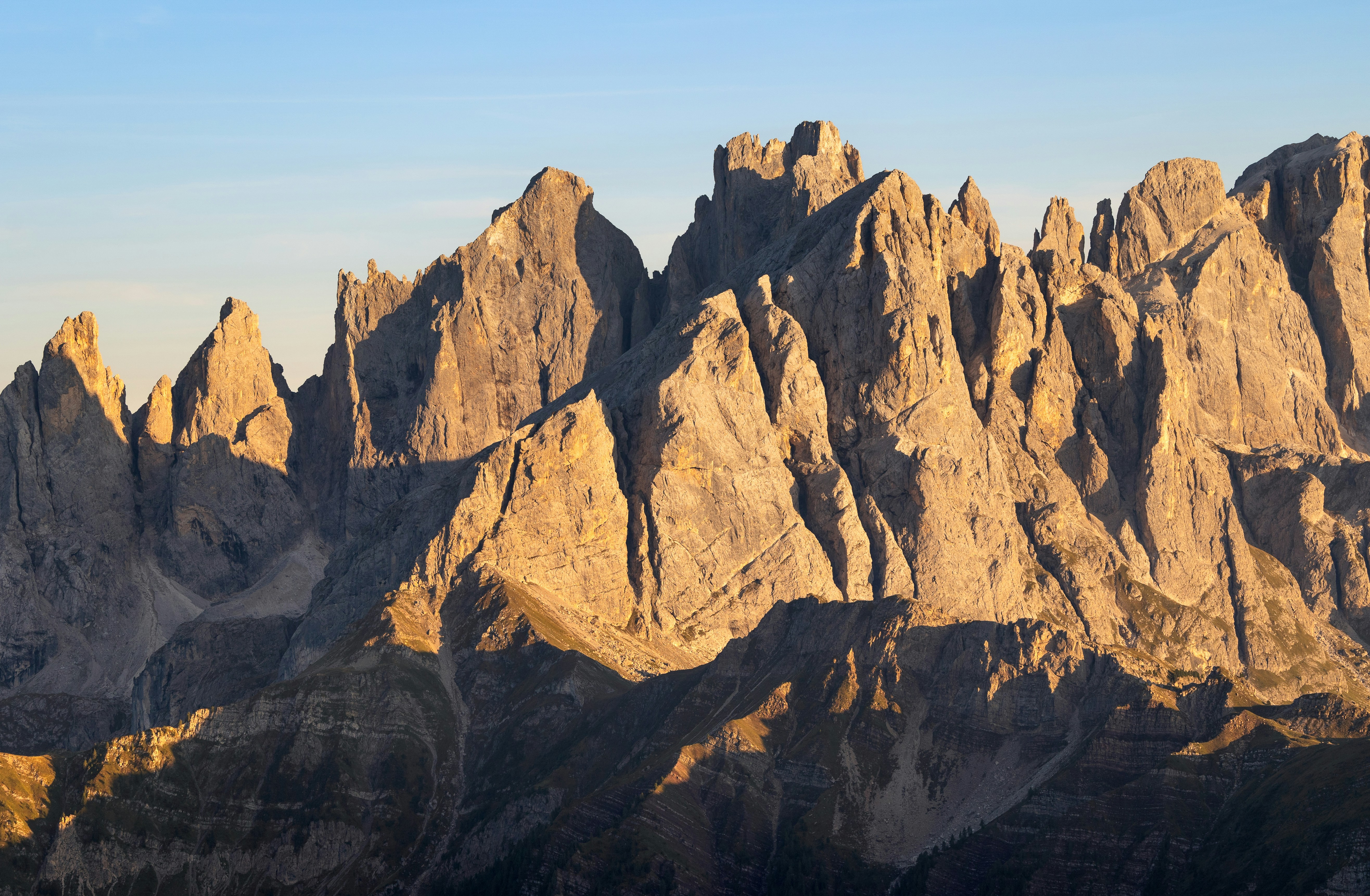 Cime frastagliate di montagna illuminate da una luce dorata del sole.