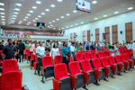 People standing in a large hall with red seats.