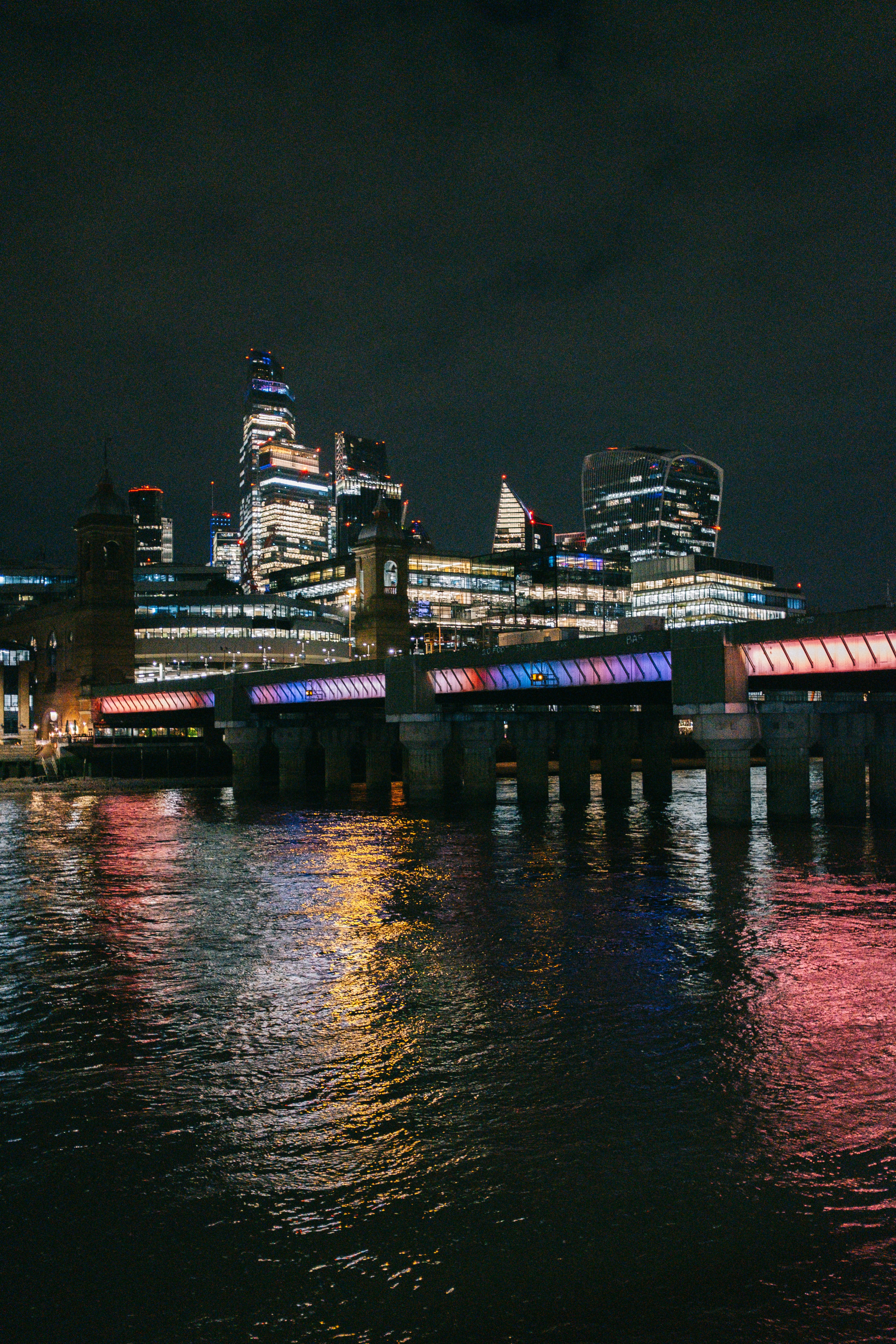 El skyline de la ciudad por la noche con luces de colores del puente reflejadas.
