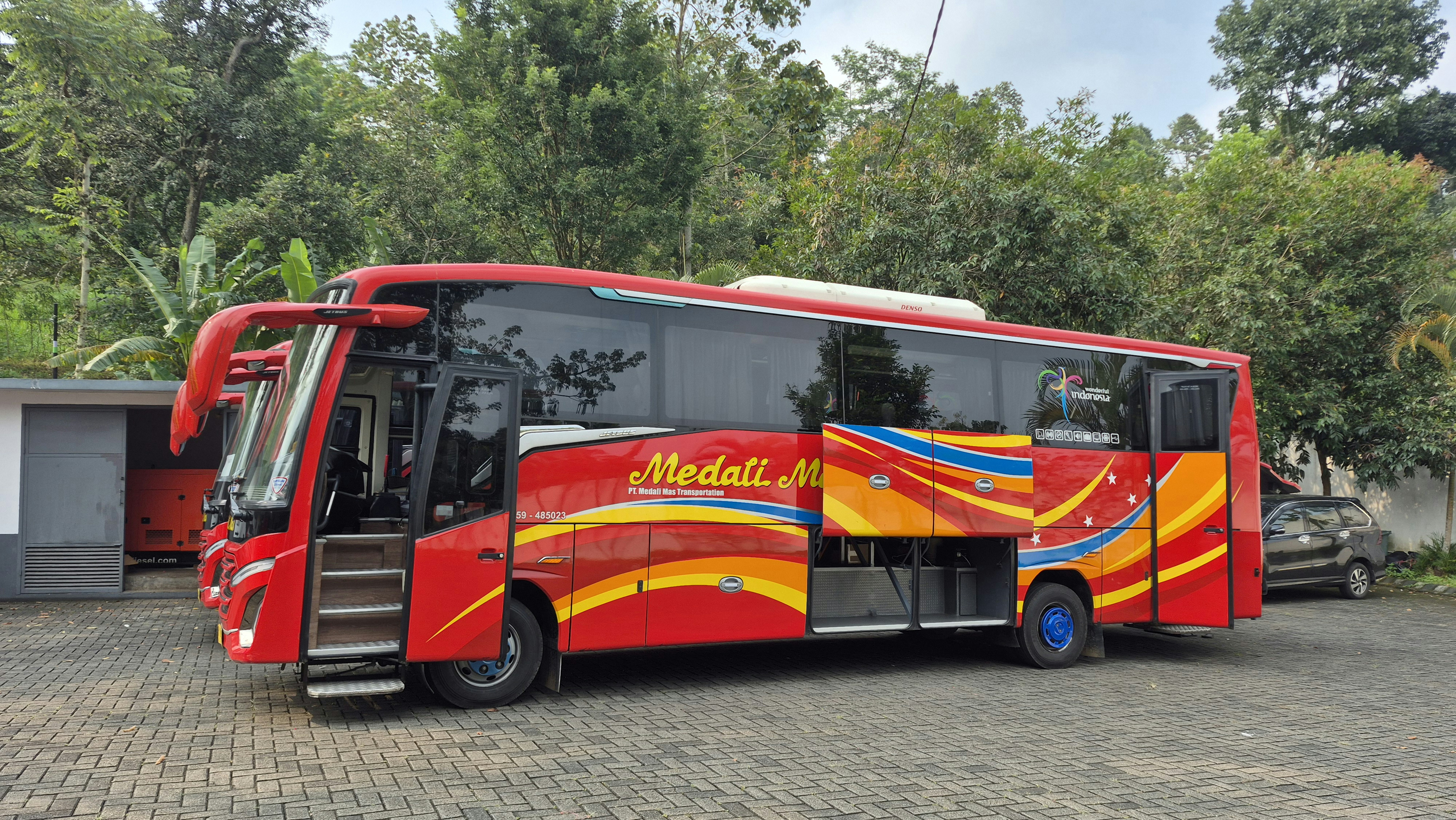 Autobús rojo "medali mas" con puerta abierta y diseños coloridos.