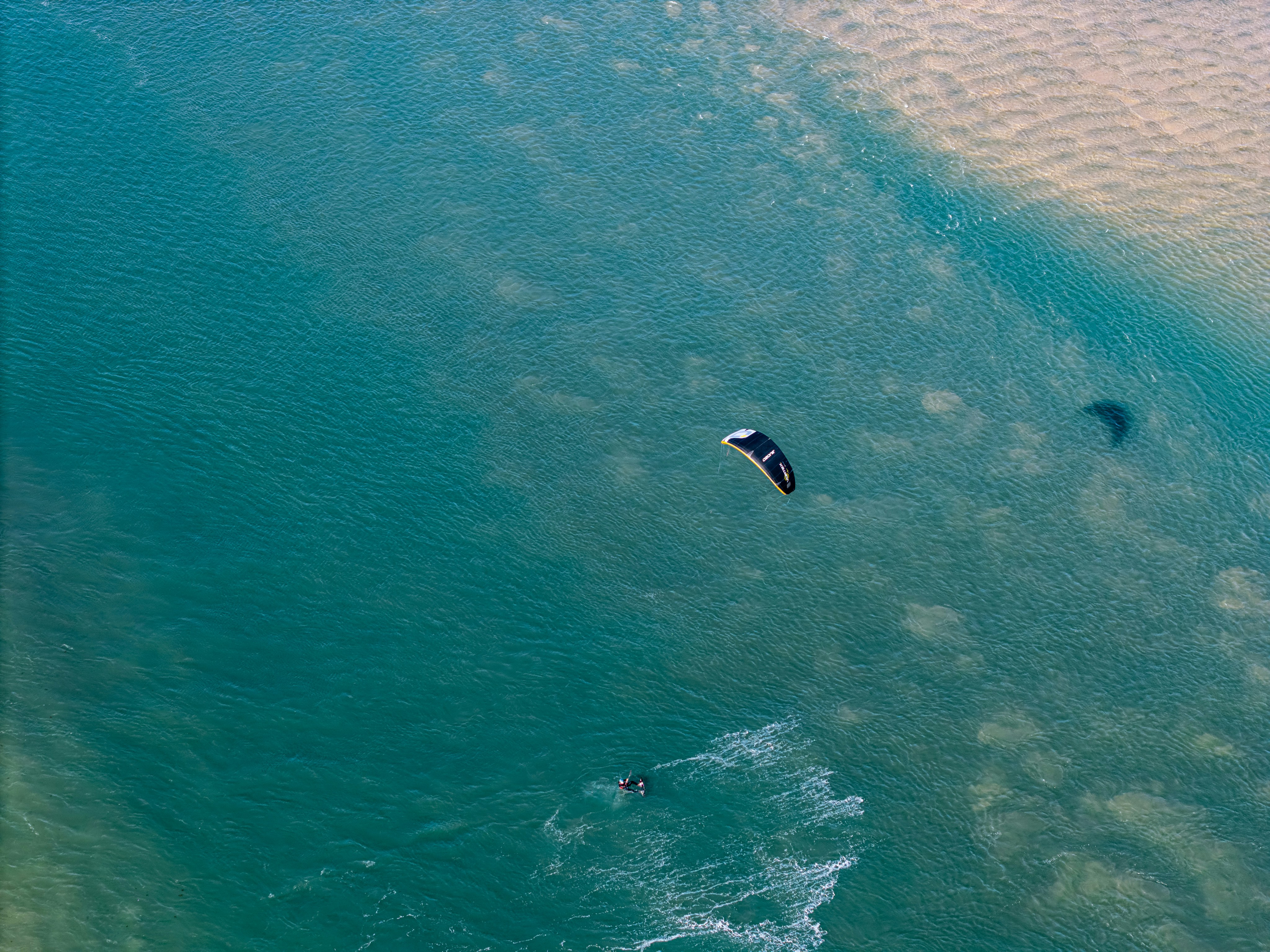 Kiteboarder gliding across turquoise ocean water