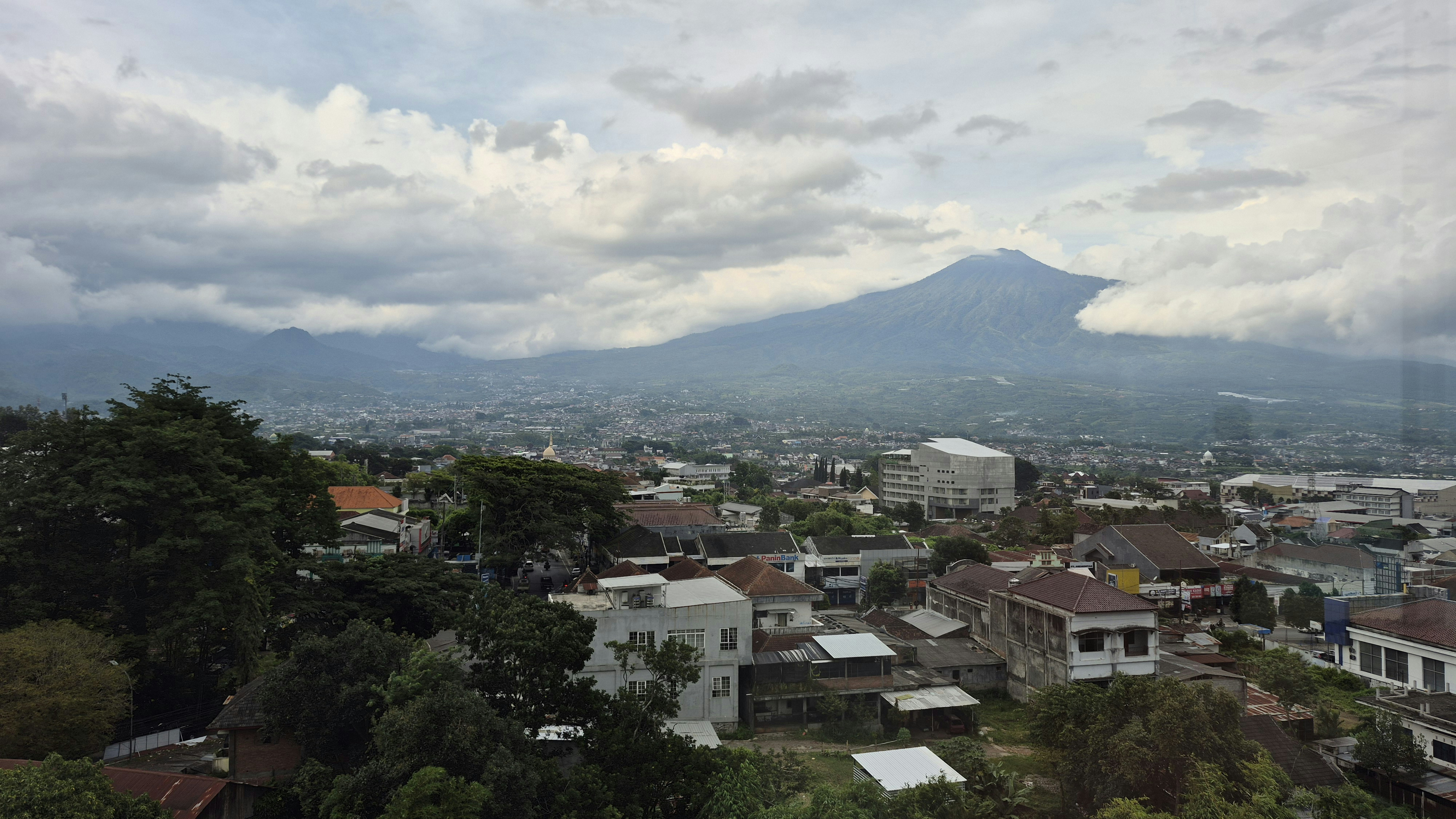 Una ciudad enclavada bajo una majestuosa montaña bajo cielos nublados.