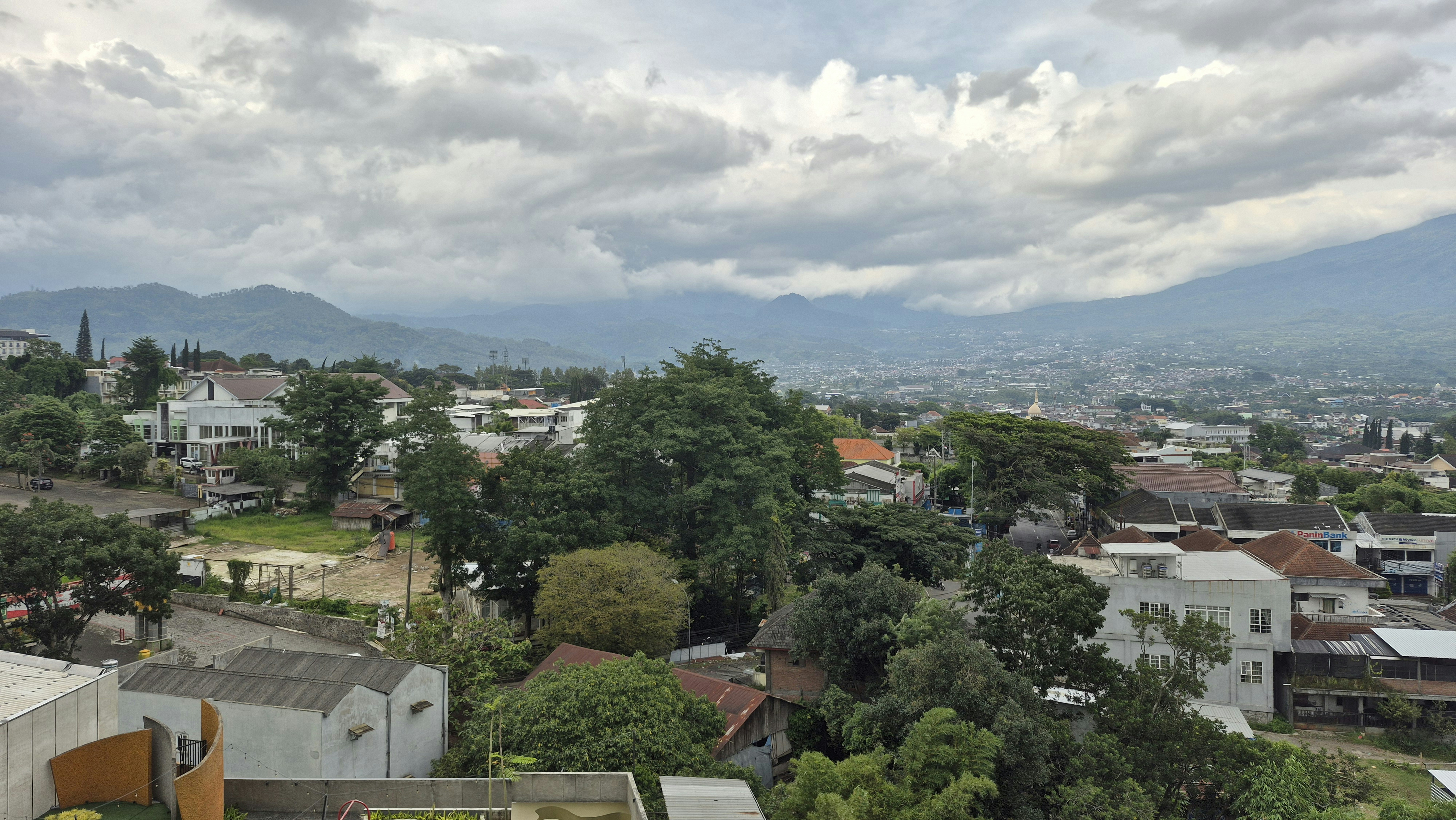 Cielo nublado sobre una ciudad extensa y montañas lejanas.