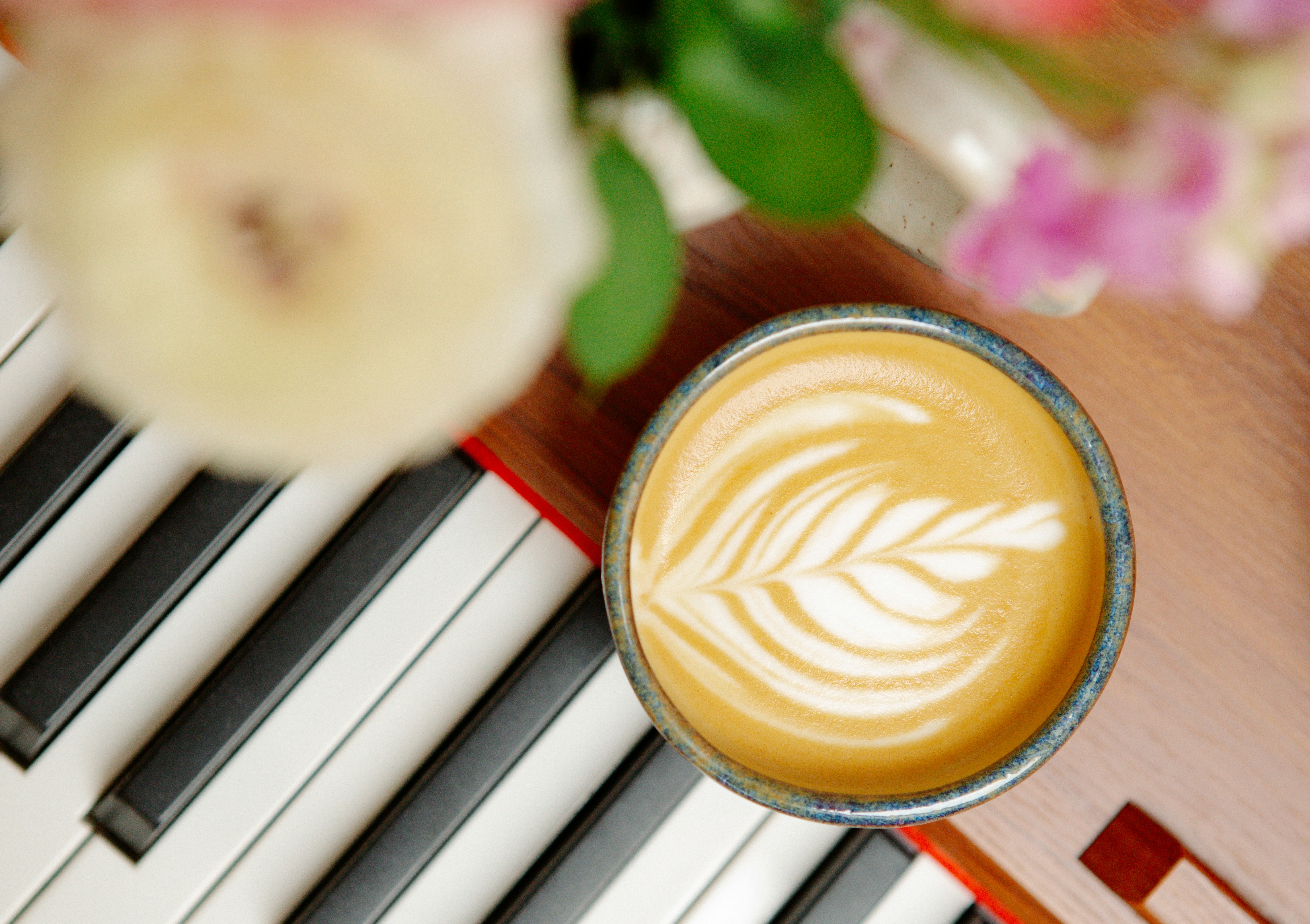 Latte art in a cup on piano keys with flowers