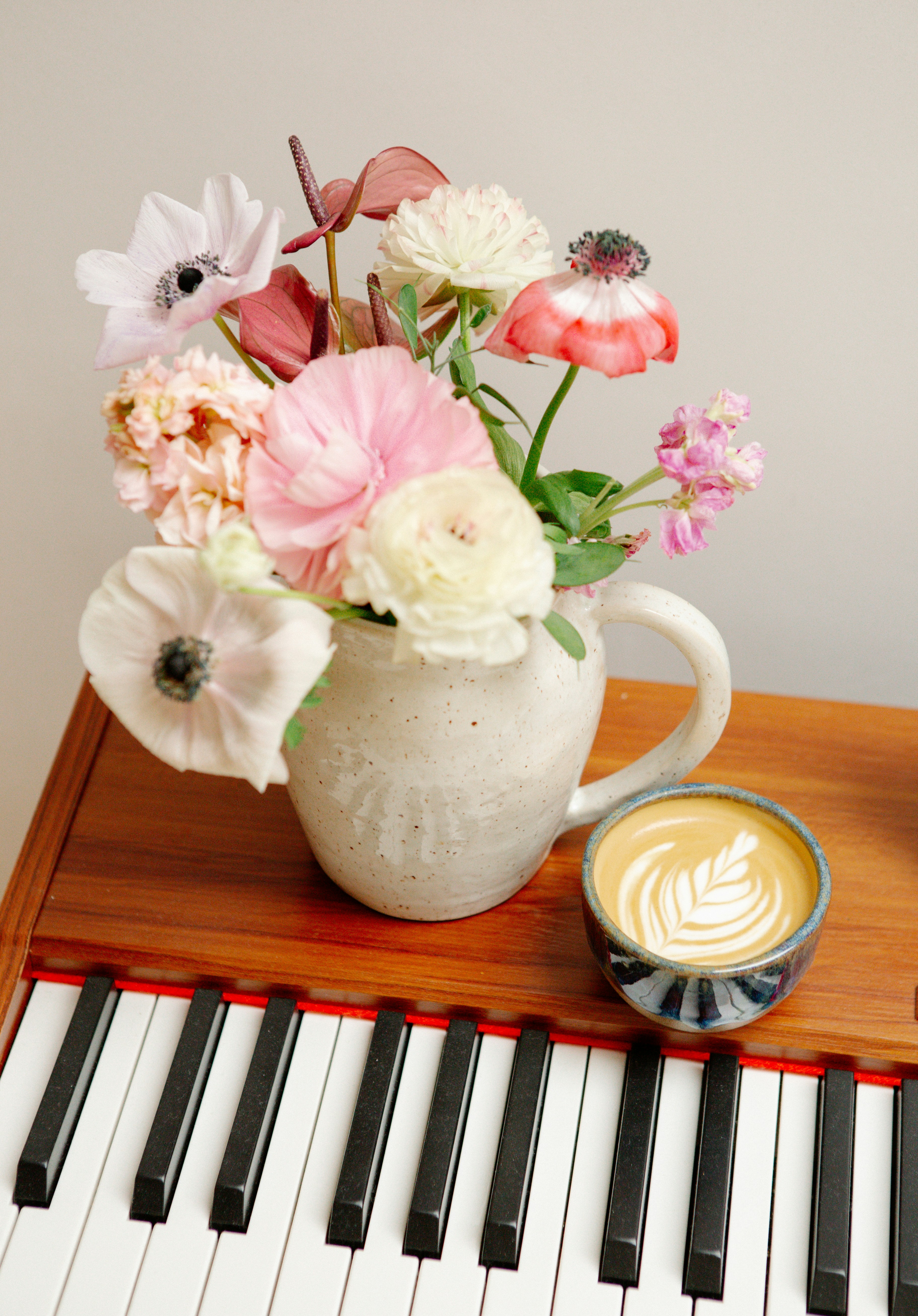 A bouquet of flowers and a latte on piano keys