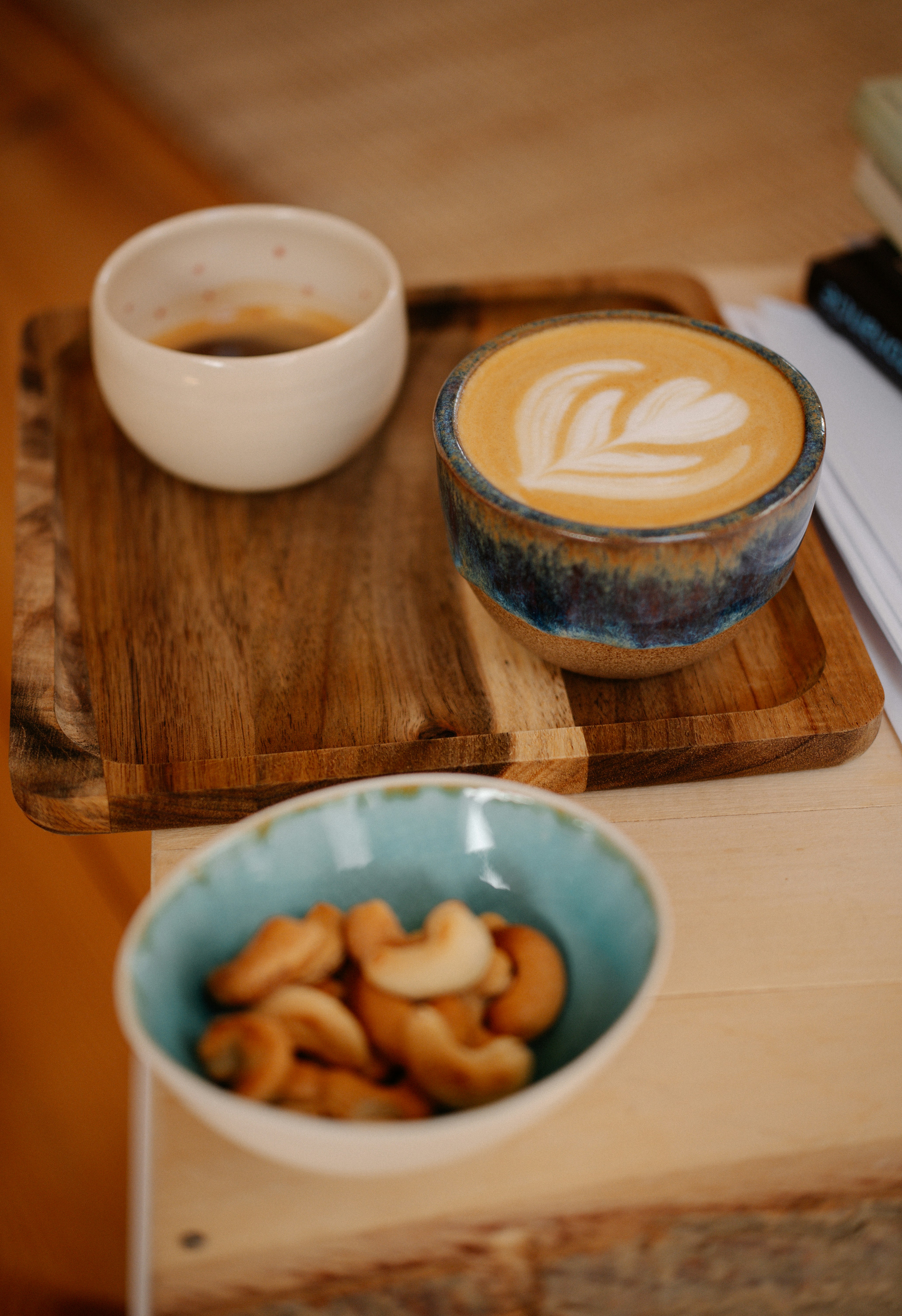 Espresso, latte art coffee, and cashews on a tray
