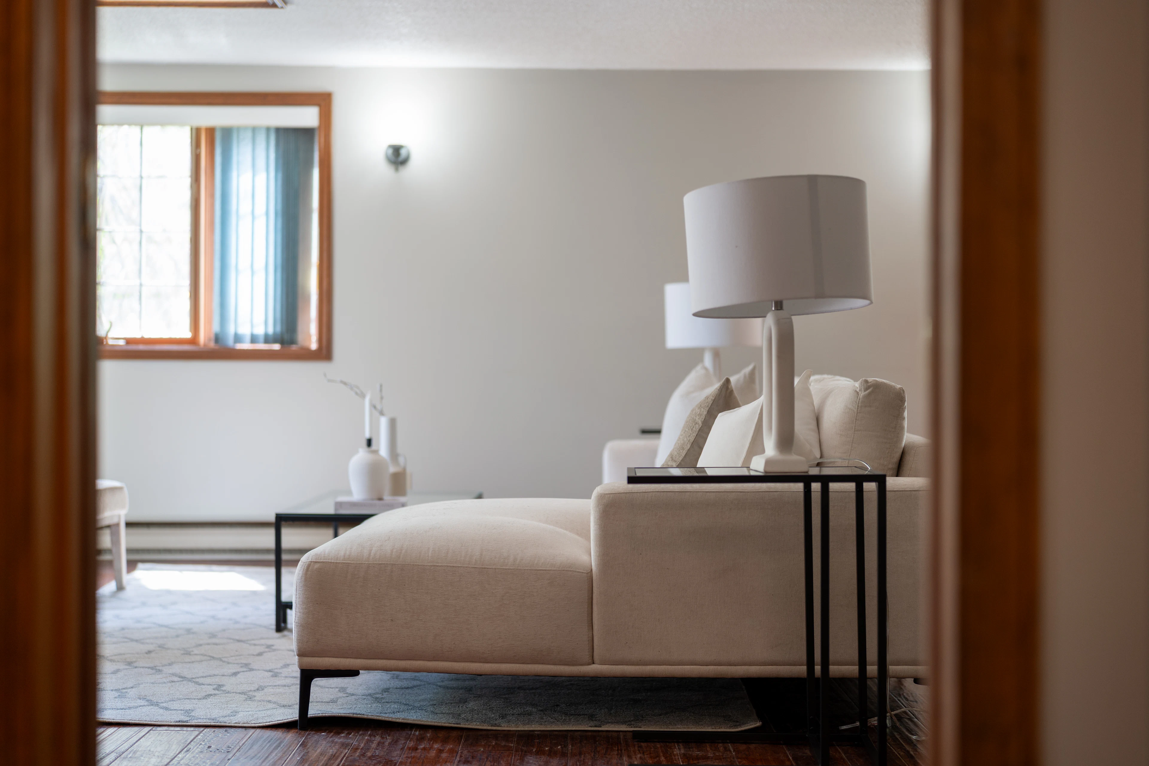 A finished living room with a white sectional sofa, table lamps and soft curtains