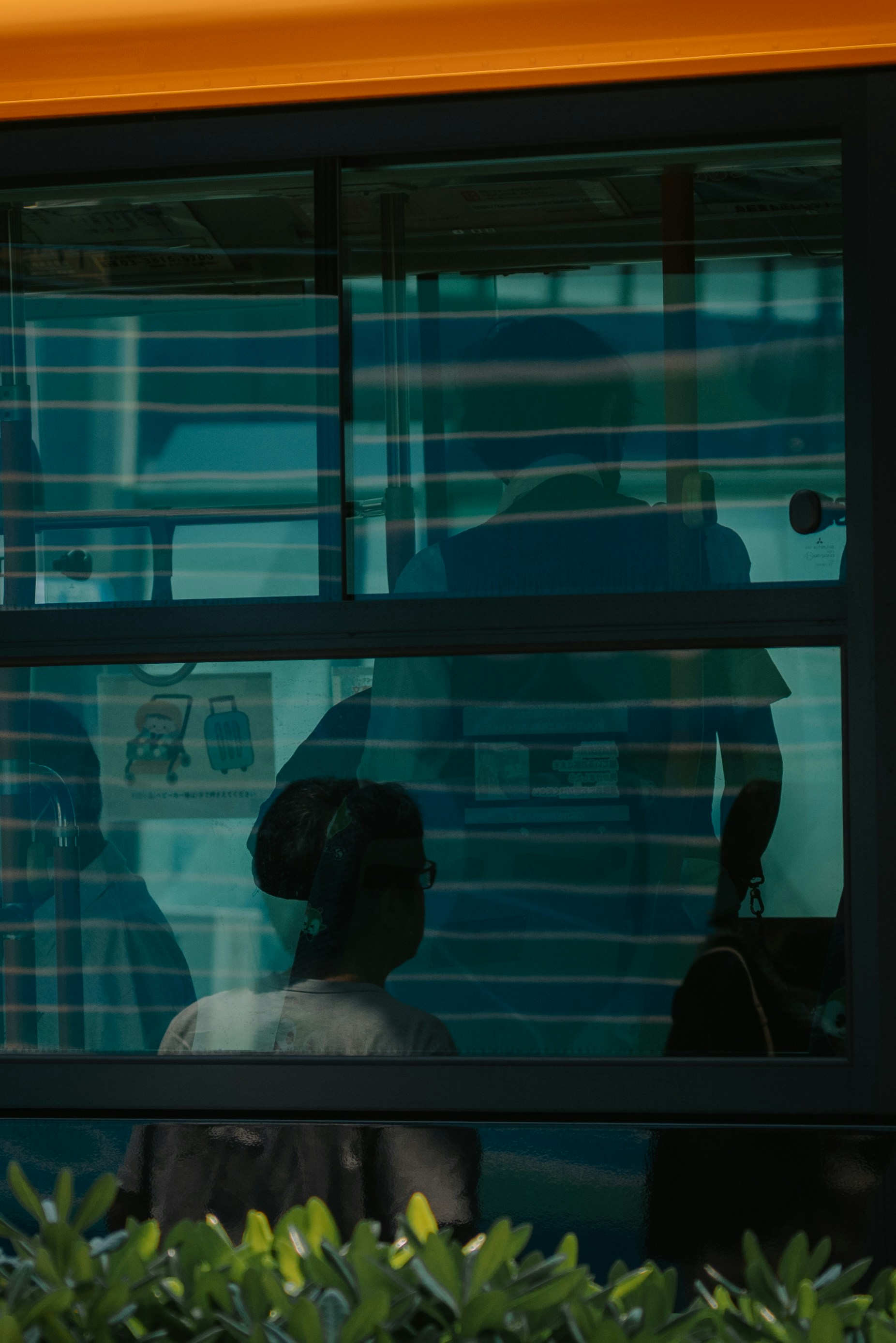 Silhouettes of people seen through a bus window
