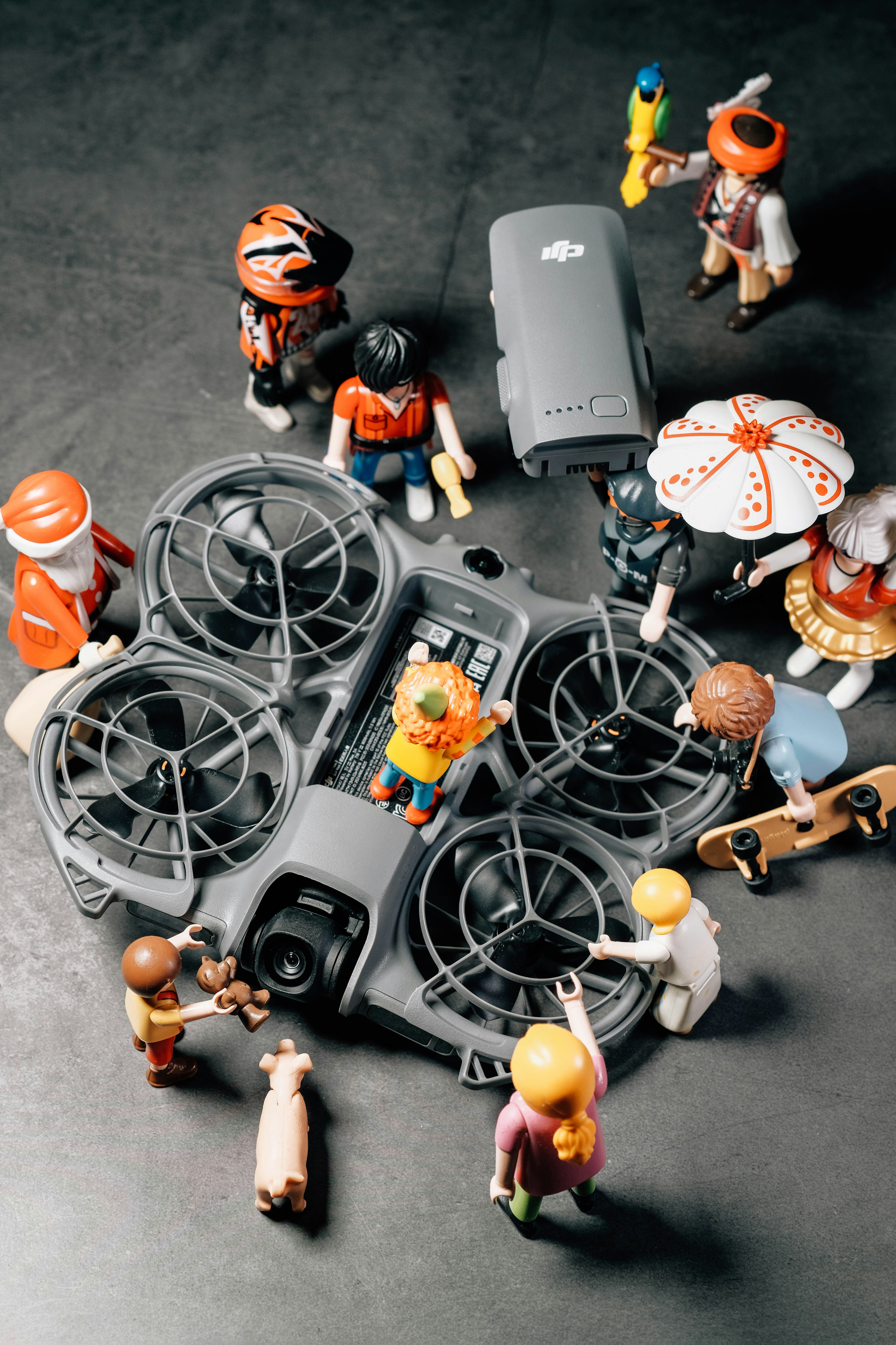 Des figurines Playmobil entourent un drone sur une surface sombre.