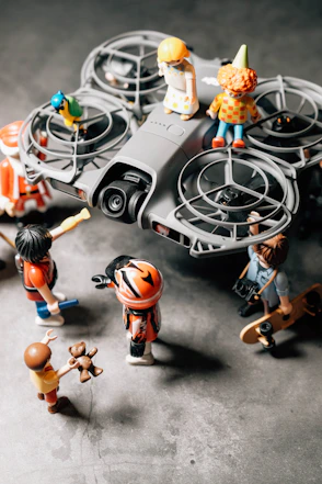 Miniature figures gathered around a small gray drone.