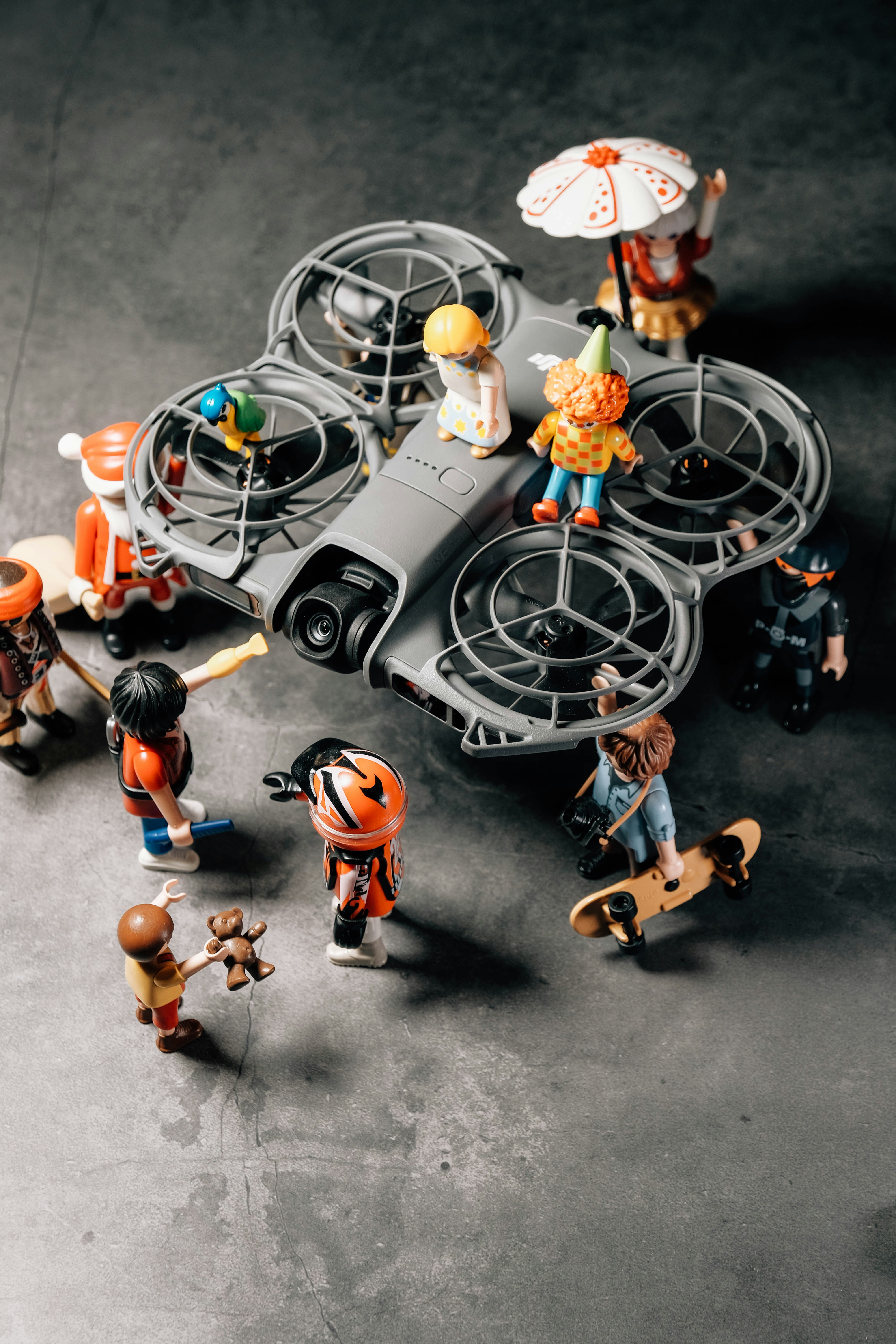 Des figurines Playmobil rassemblées autour d’un drone sur une surface sombre.
