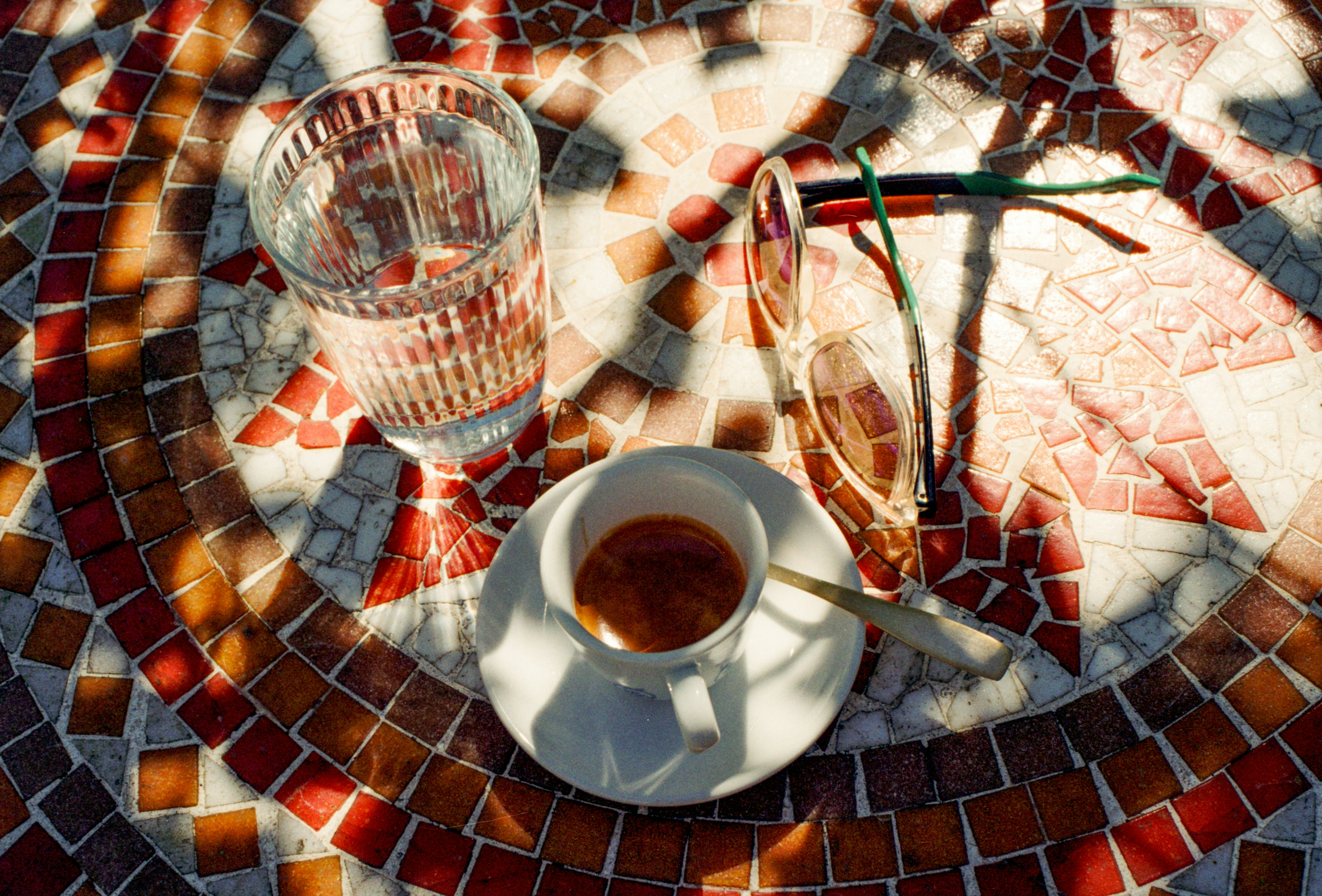 Photo of A glass of water and espresso on a mosaic table. by Chris Weiher