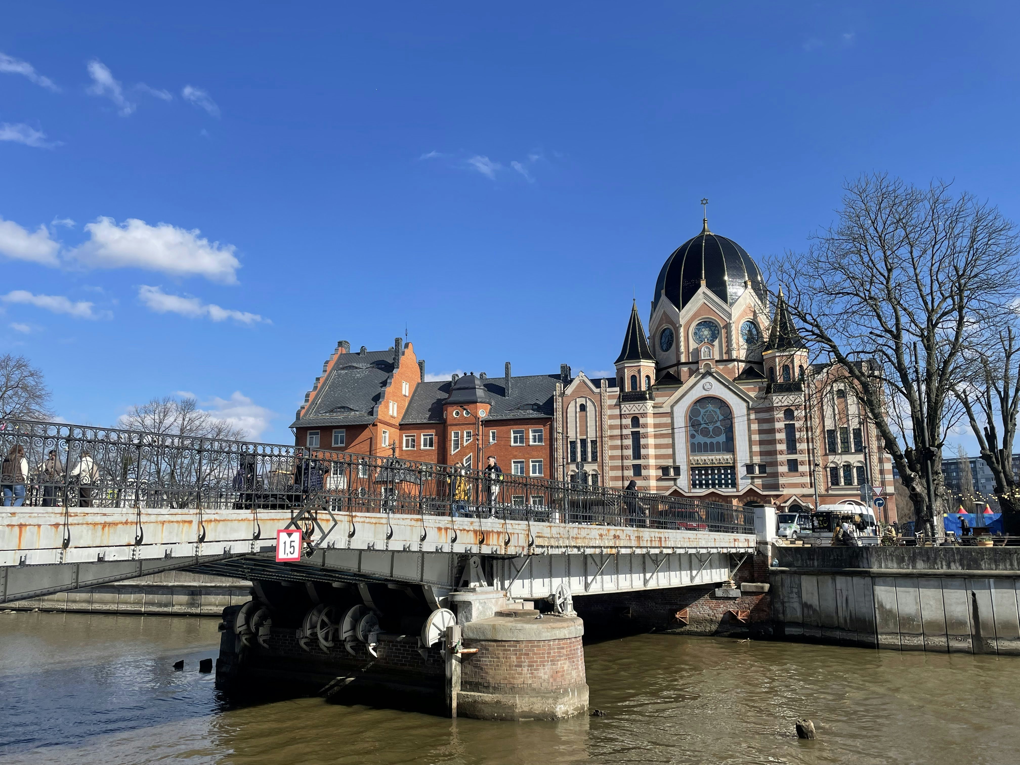 Ornate synagogue and bridge over water under a clear sky.