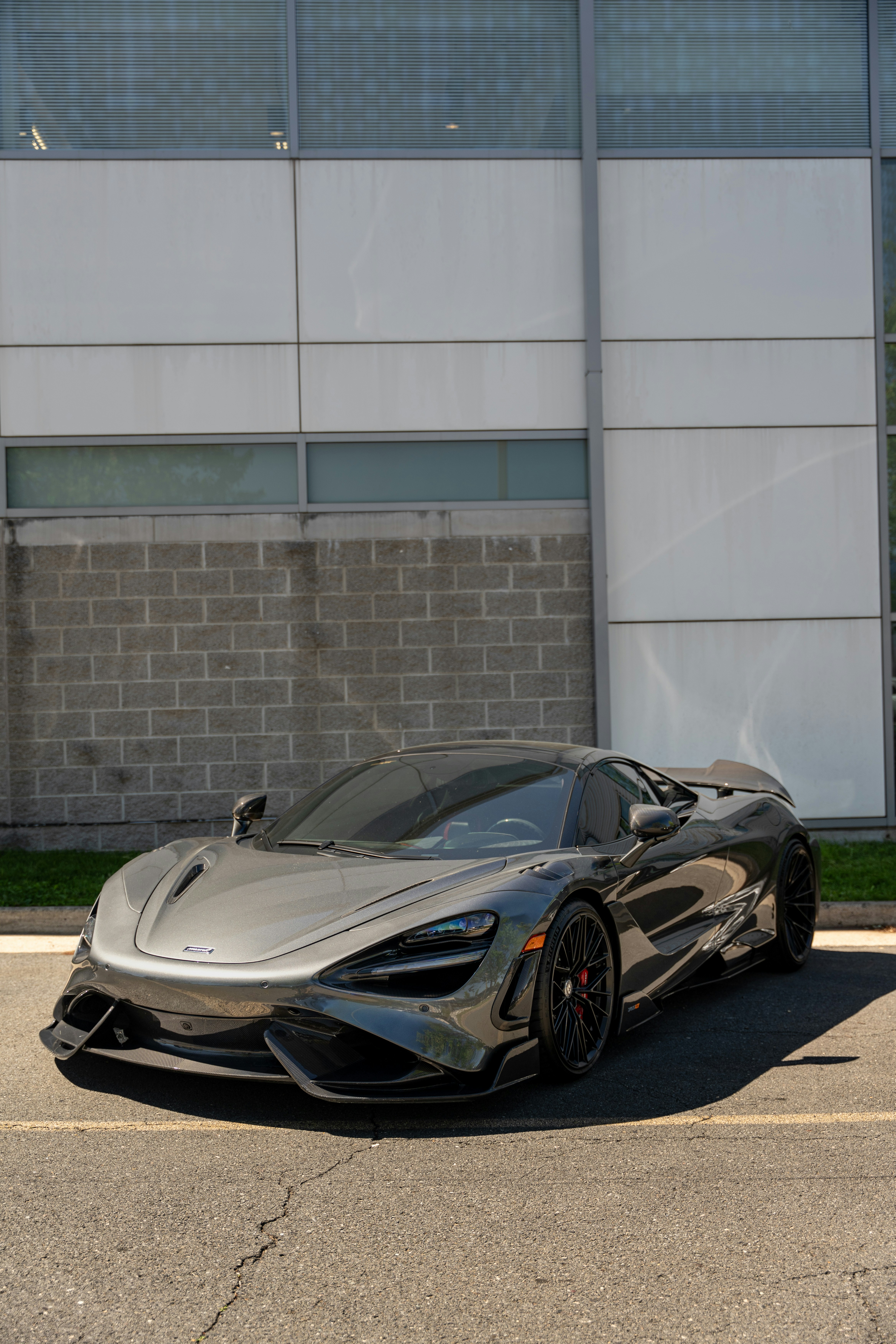 Sleek dark gray sports car parked by a modern building