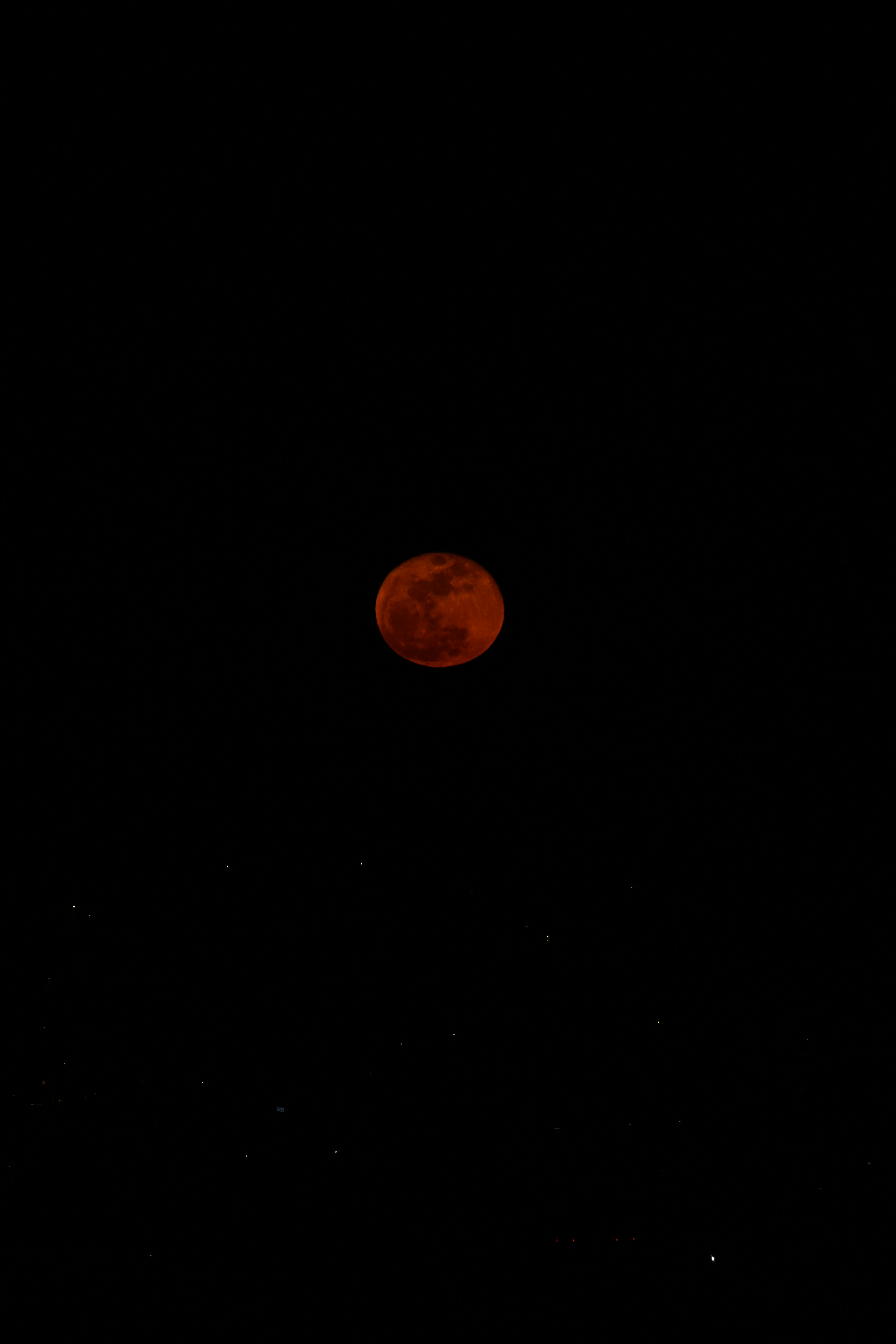 Lune rouge de sang dans un ciel nocturne sombre et étoilé.