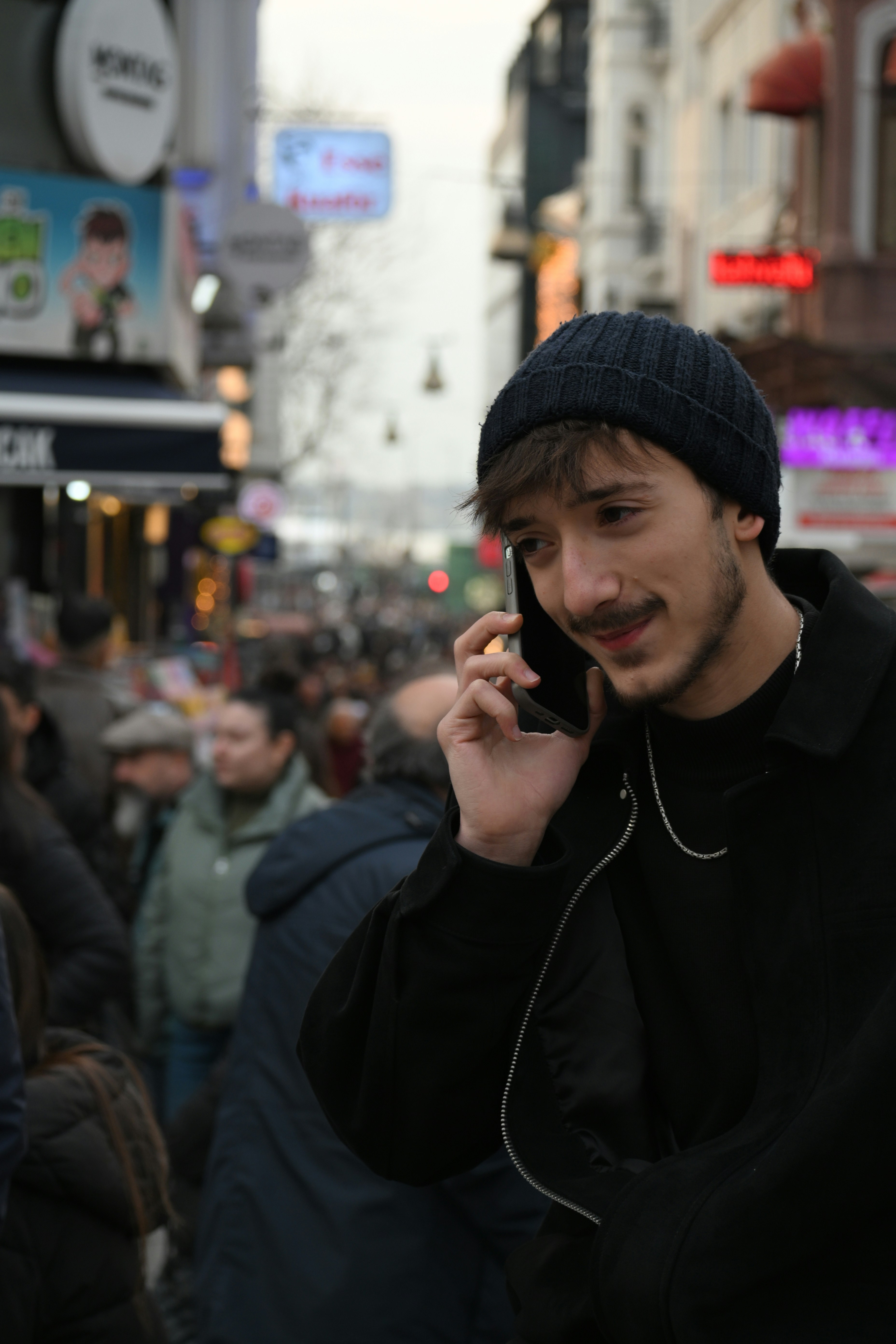 Un homme en bonnet parle au téléphone dans une rue urbaine animée.