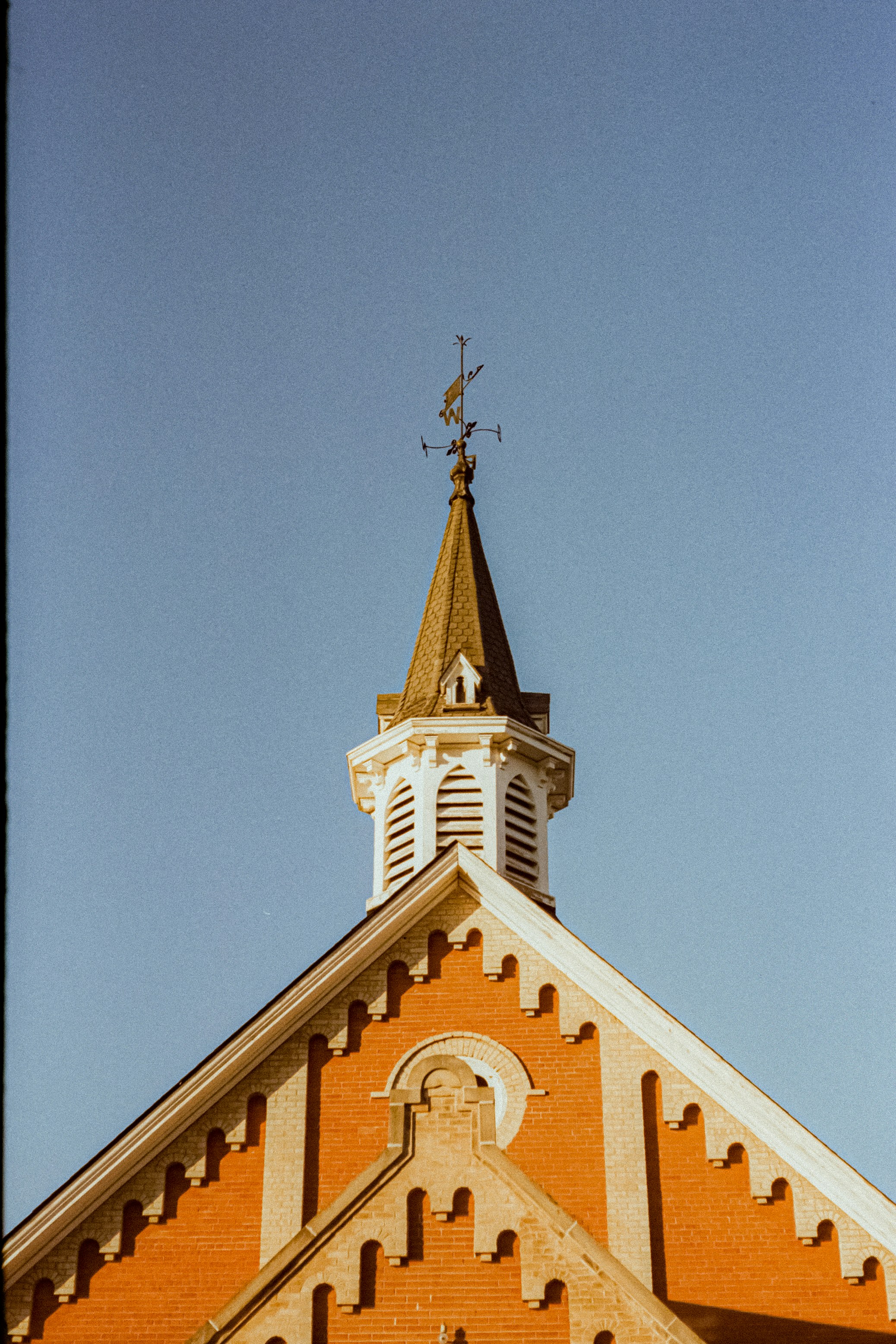Photo of Steeple with weather vane against a clear blue sky by Linus Belanger