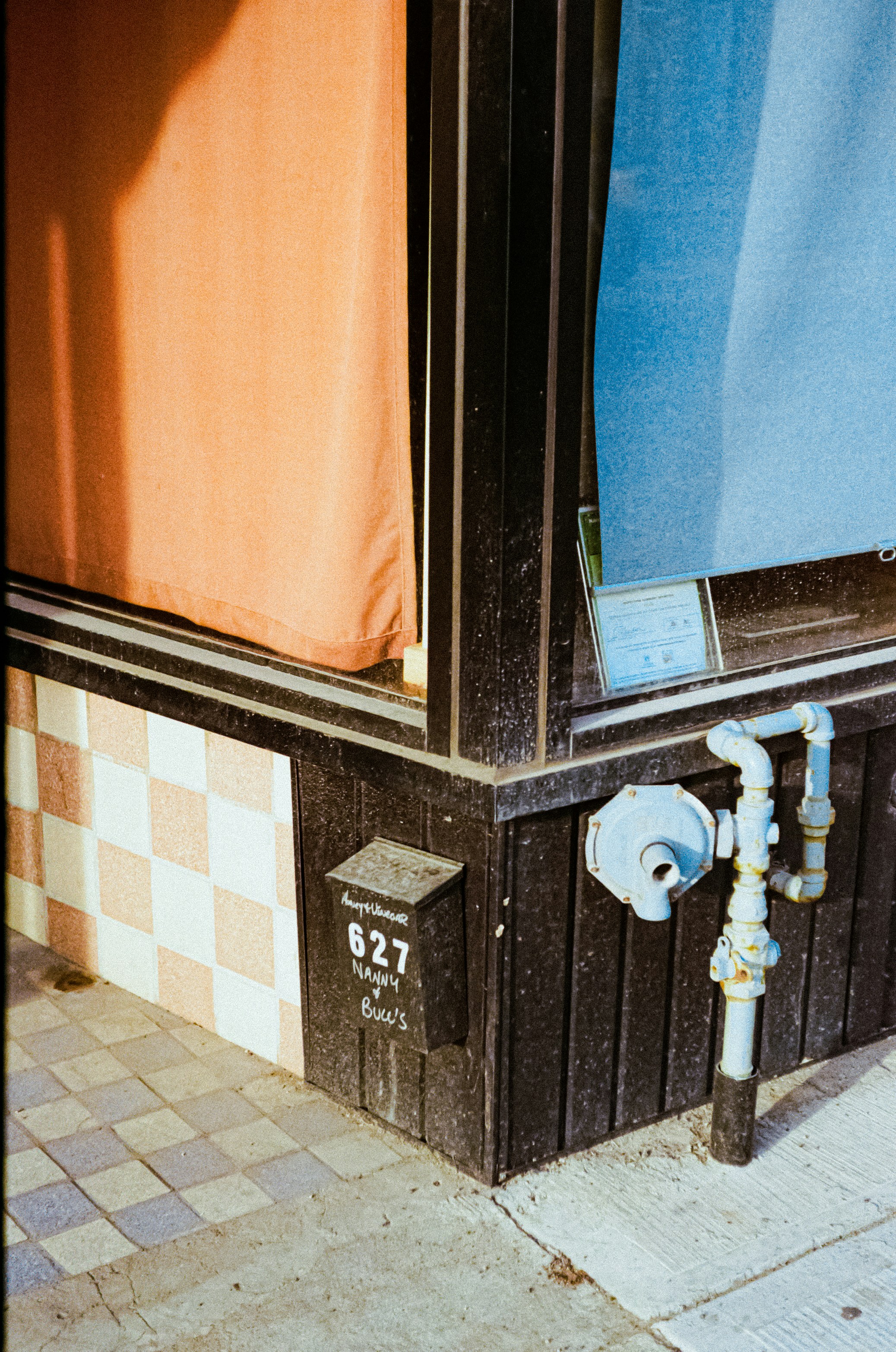 Photo of Corner of a building with orange and blue curtains by Linus Belanger