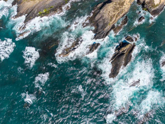 Waves crashing on rocky coastline from above