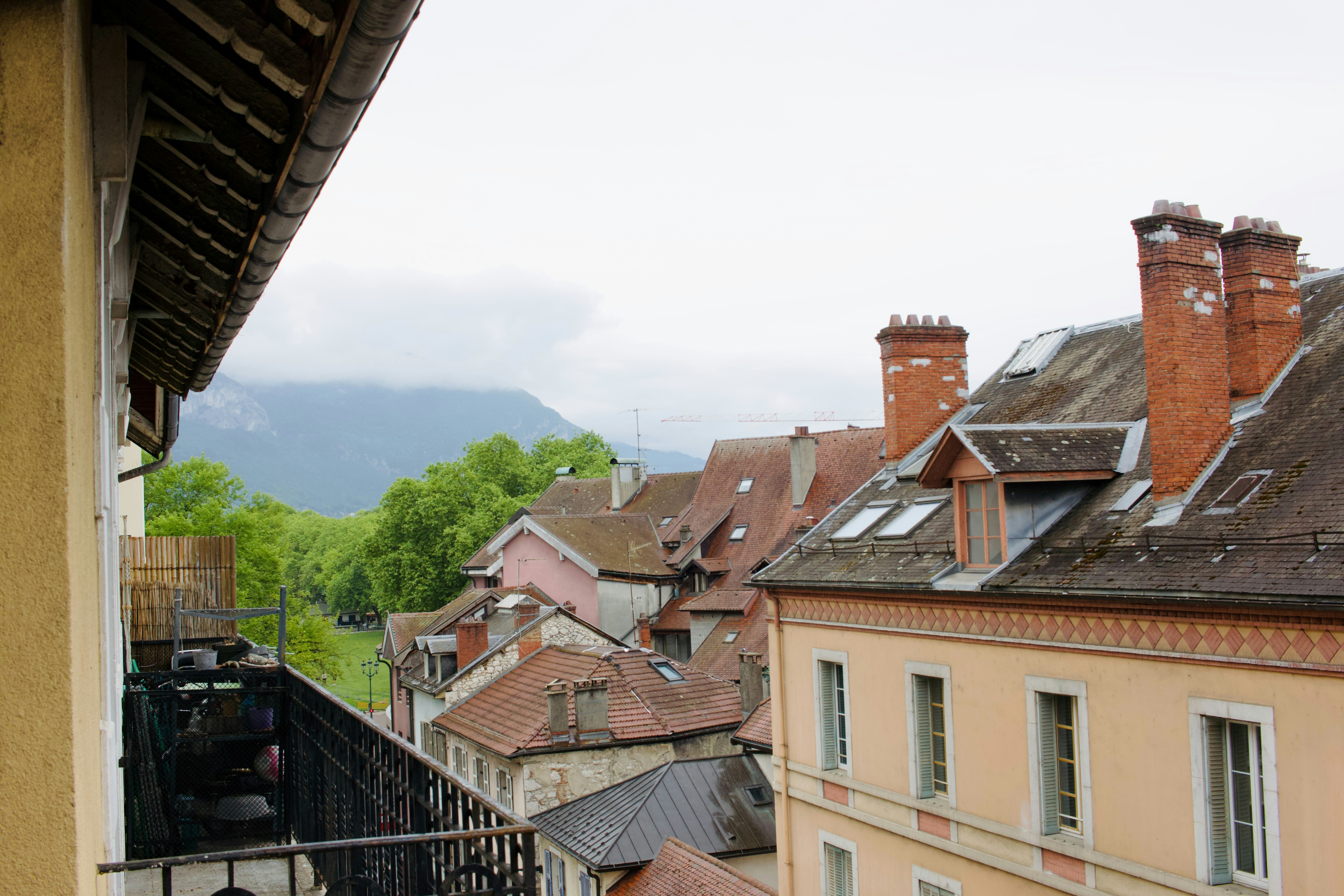 Rooftops of old buildings with chimneys under cloudy sky.
