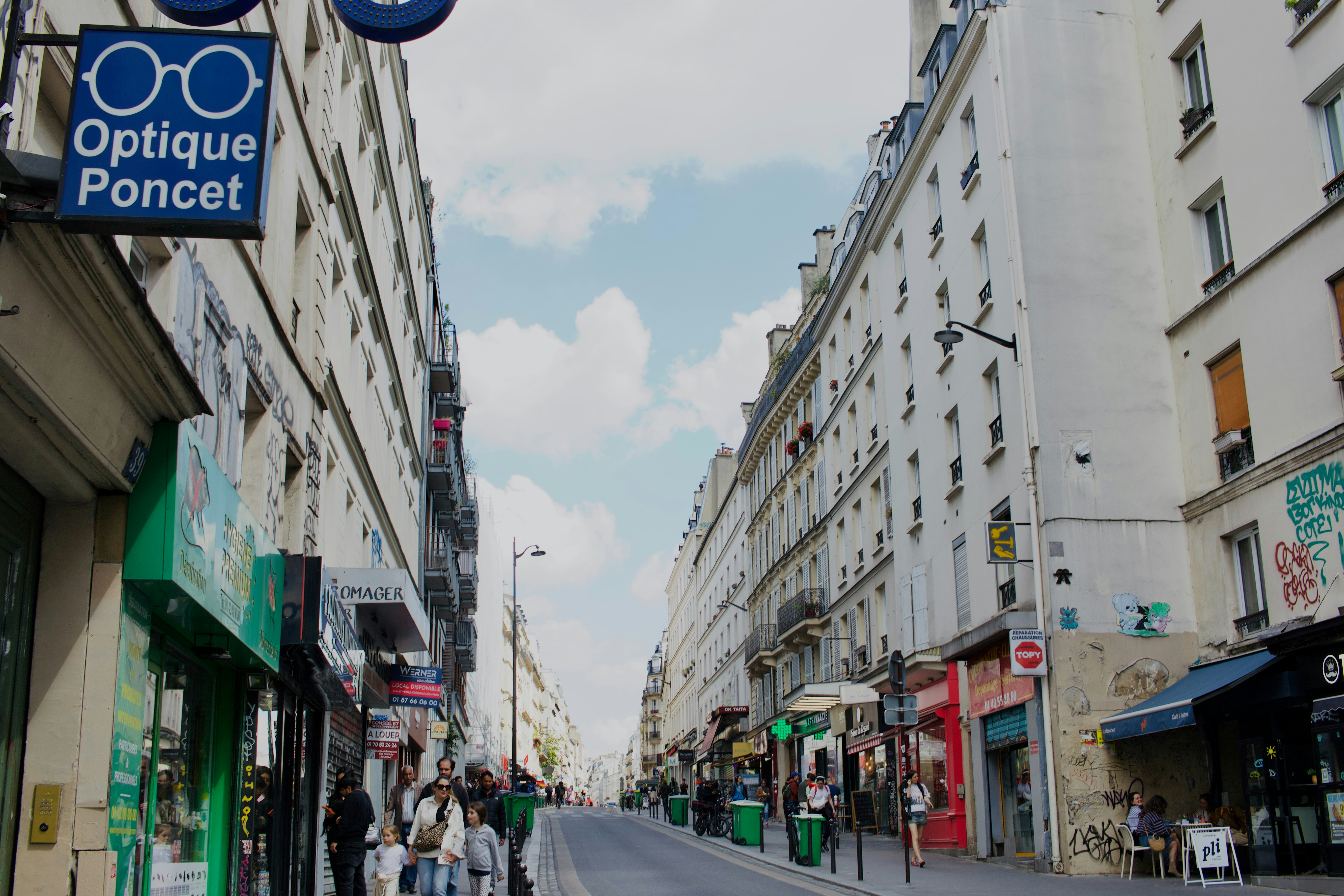 Street lined with buildings and shops under a cloudy sky.