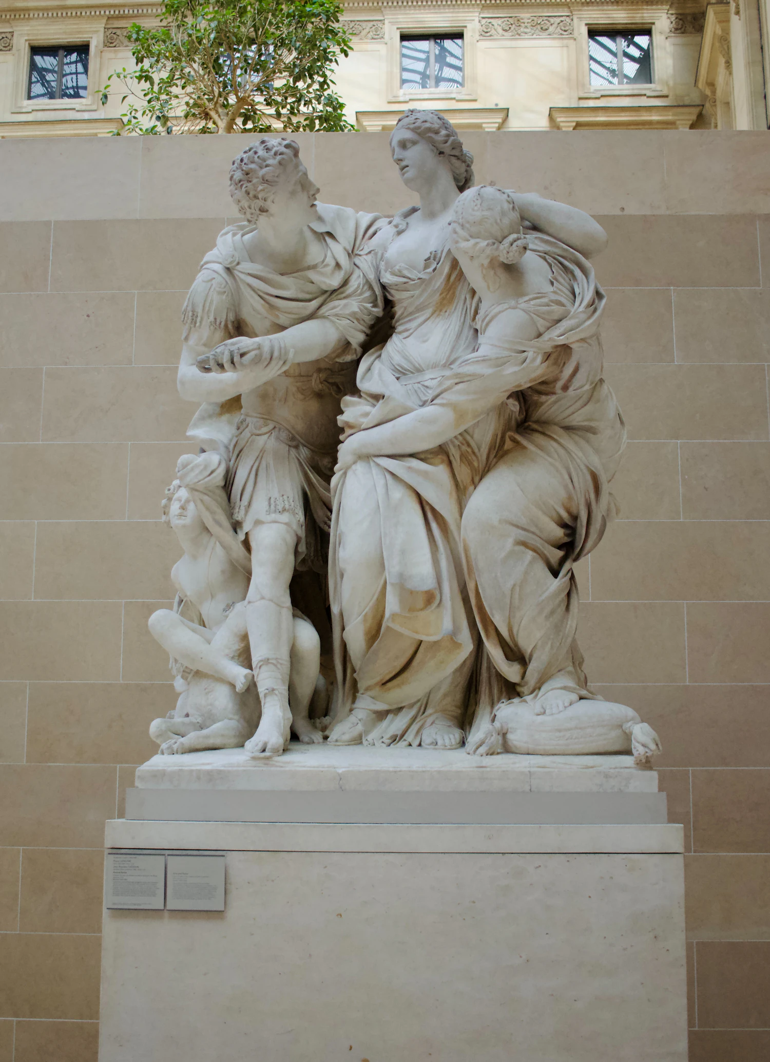 A marble group of three carved figures on a shared pedestal