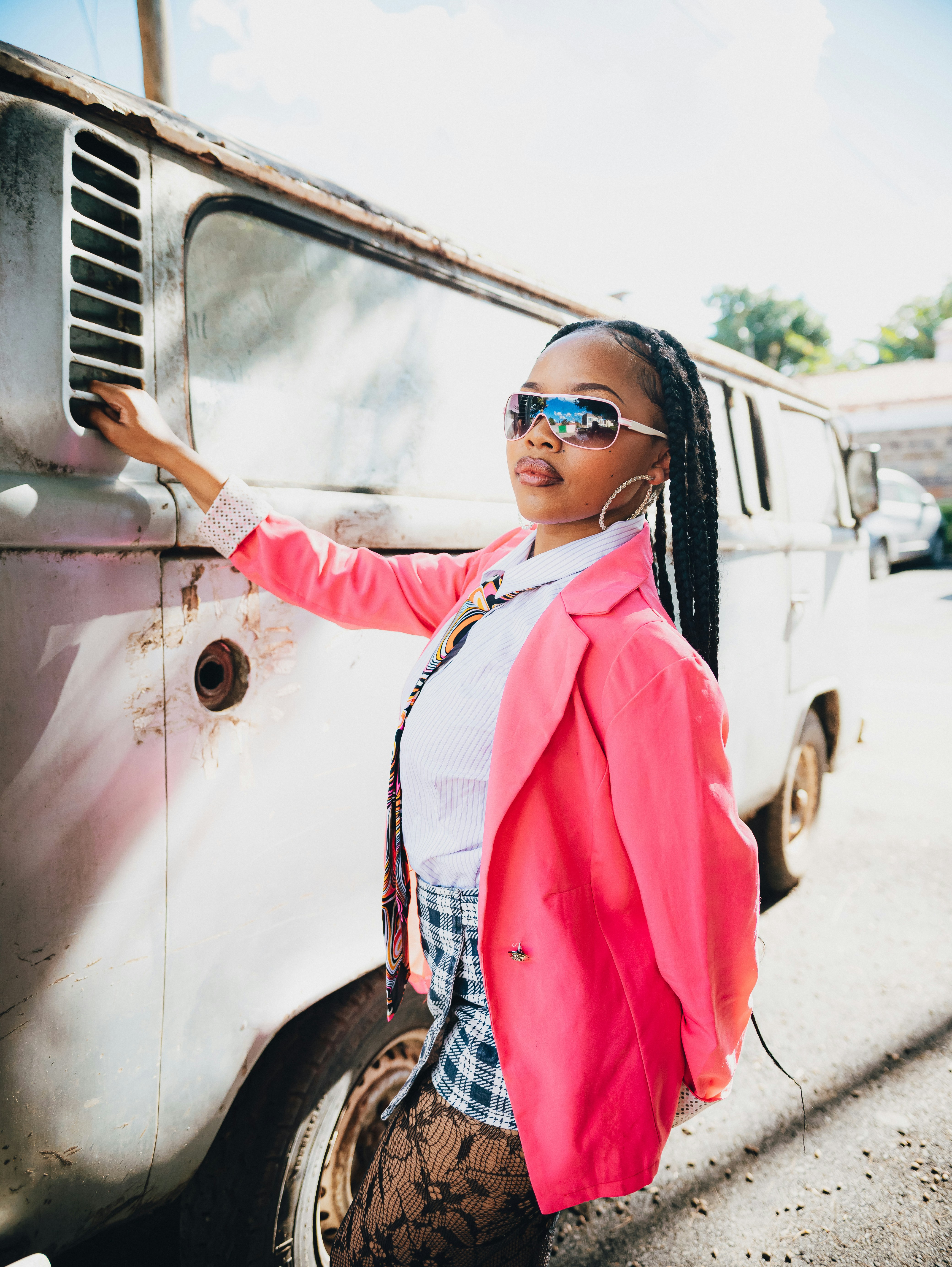 Mulher de blazer rosa se apoia em uma van vintage