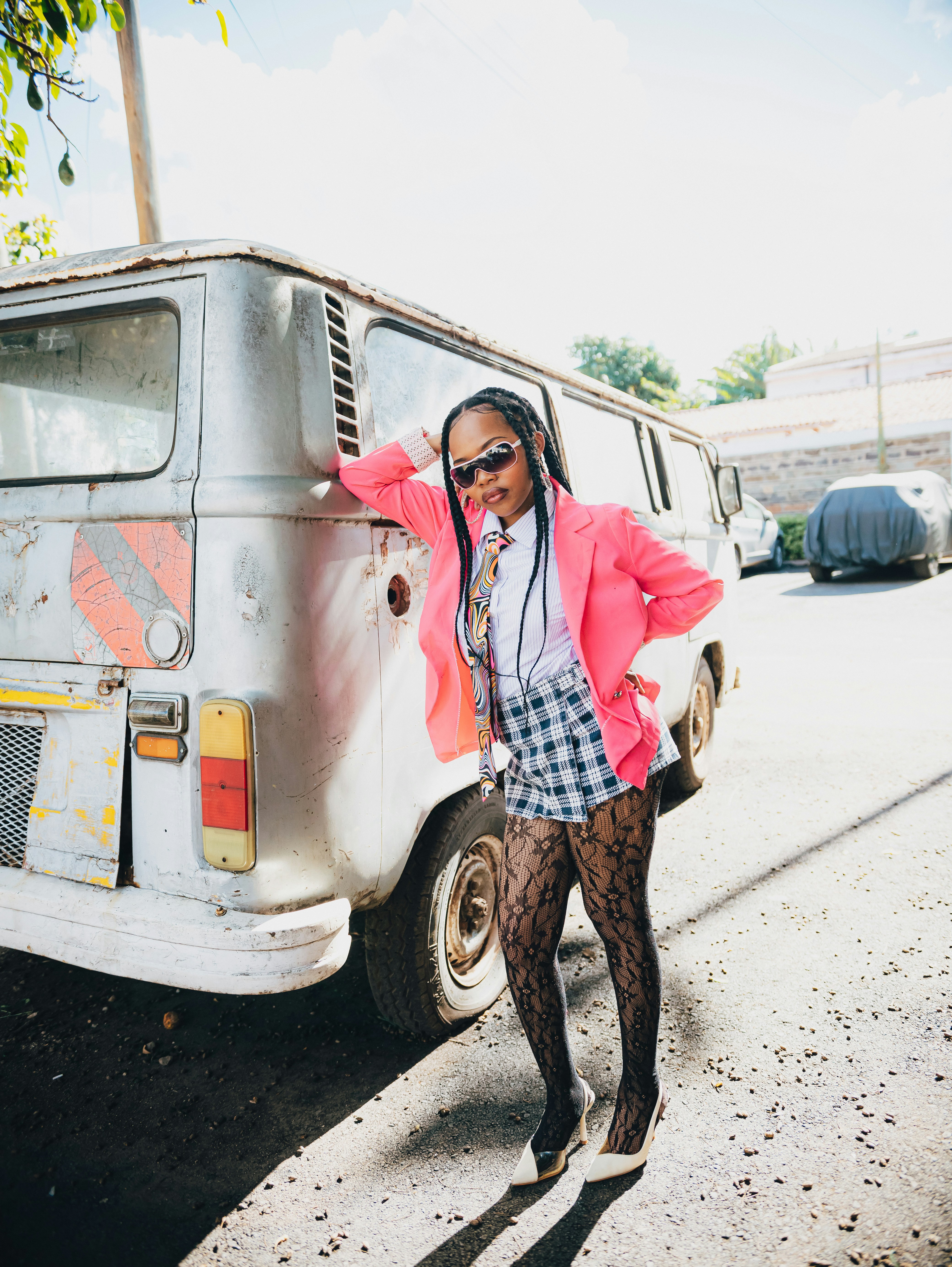 Mulher de blazer rosa se apoia em uma van vintage